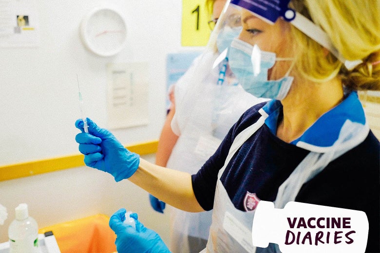 A woman wearing a mask, a face shield, and gloves holds a syringe in front of her, with a colleague in PPE standing beside her and a whiteboard in the background