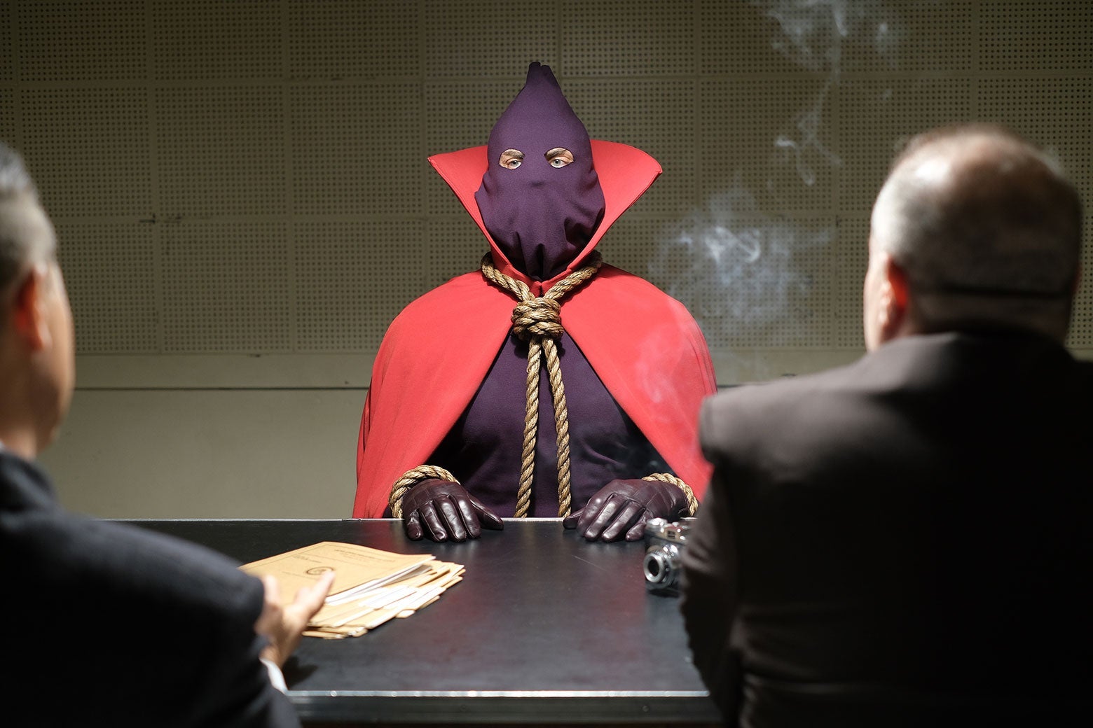 Hooded Justice sits at a table in an interrogation room in this still from HBO's Watchmen.