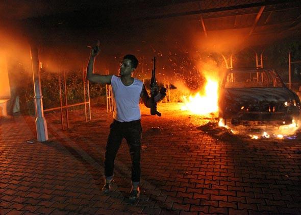 This file photo taken on September 11, 2012 shows an armed man waving his rifle as buildings and cars are engulfed in flames after being set on fire inside the US consulate compound in Benghazi. 