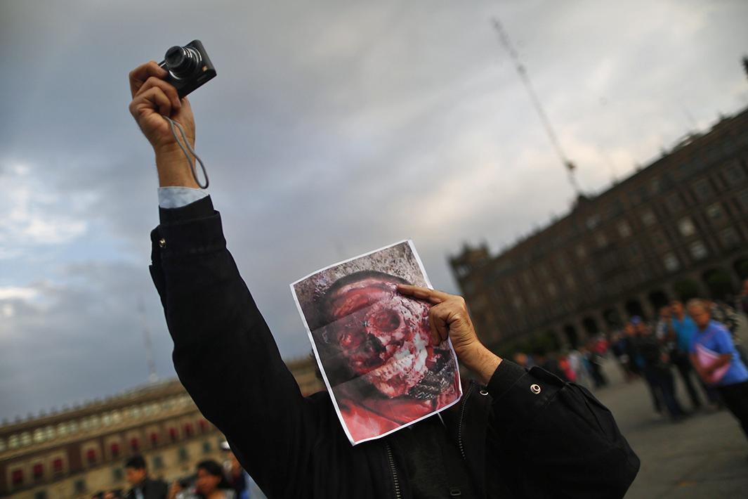 A demonstrator holds a picture of an unidentified dead person during a protest in support of the missing Ayotzinapa students in Mexico City’s Zocalo Square on Nov. 8