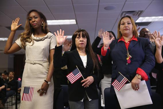 Immaculee Ilibagiza, from Rwanda, (L) and other immigrants take the oath of American citizenship at a naturalization ceremony on April 17, 2013 in New York City. Fifty immigrants from 15 countries became American citizens at the ceremony held by the U.S. Citizenship and Immigration Services (USCIS). 