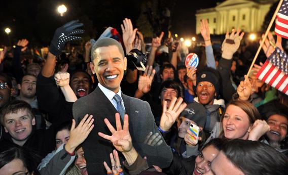 People celebrate in front of the White House with a cardboard cutout of the President Obama.