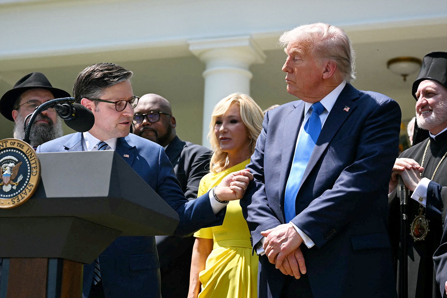 Johnson gestures towards Trump, who crosses his arms and looks ahead.
