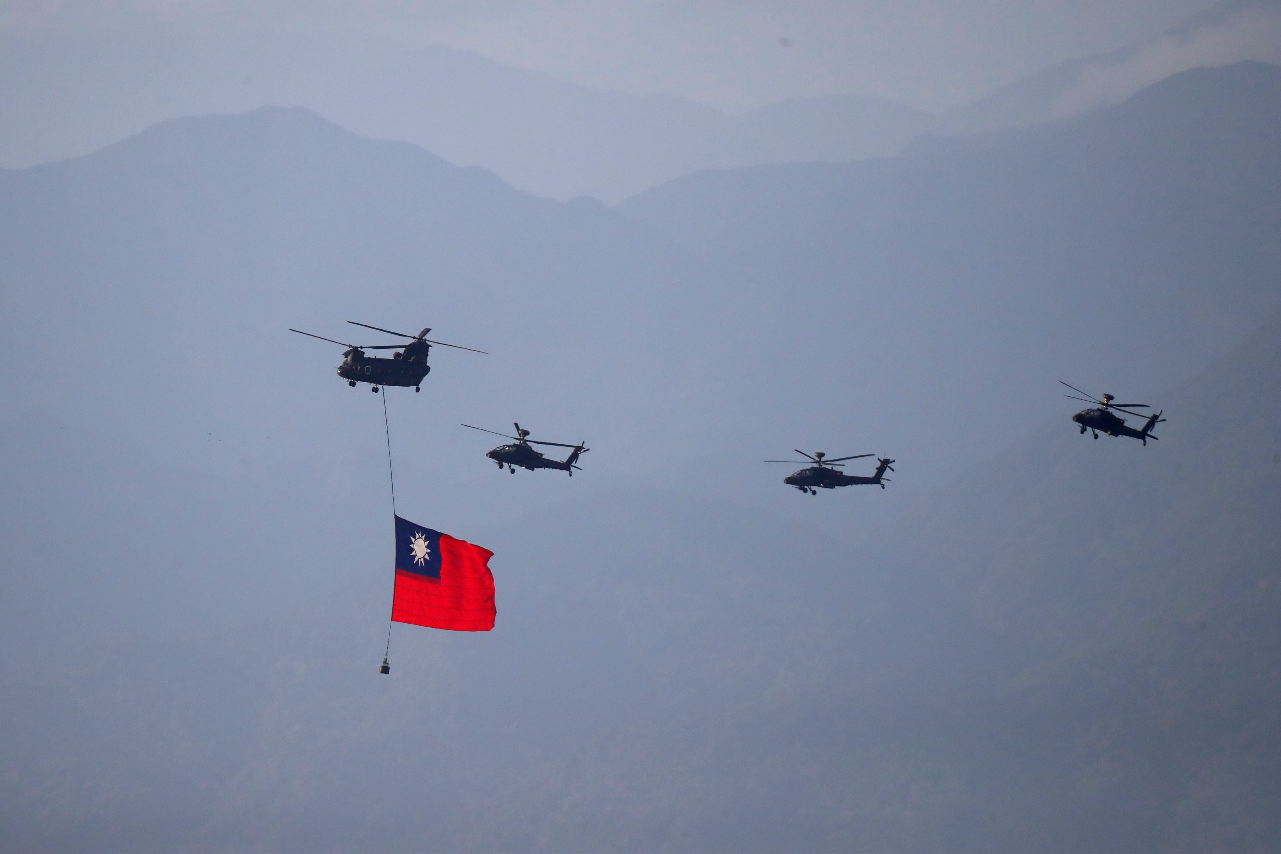 Four military helicopters are seen flying, with the leftmost chopper carrying a Taiwan flag.