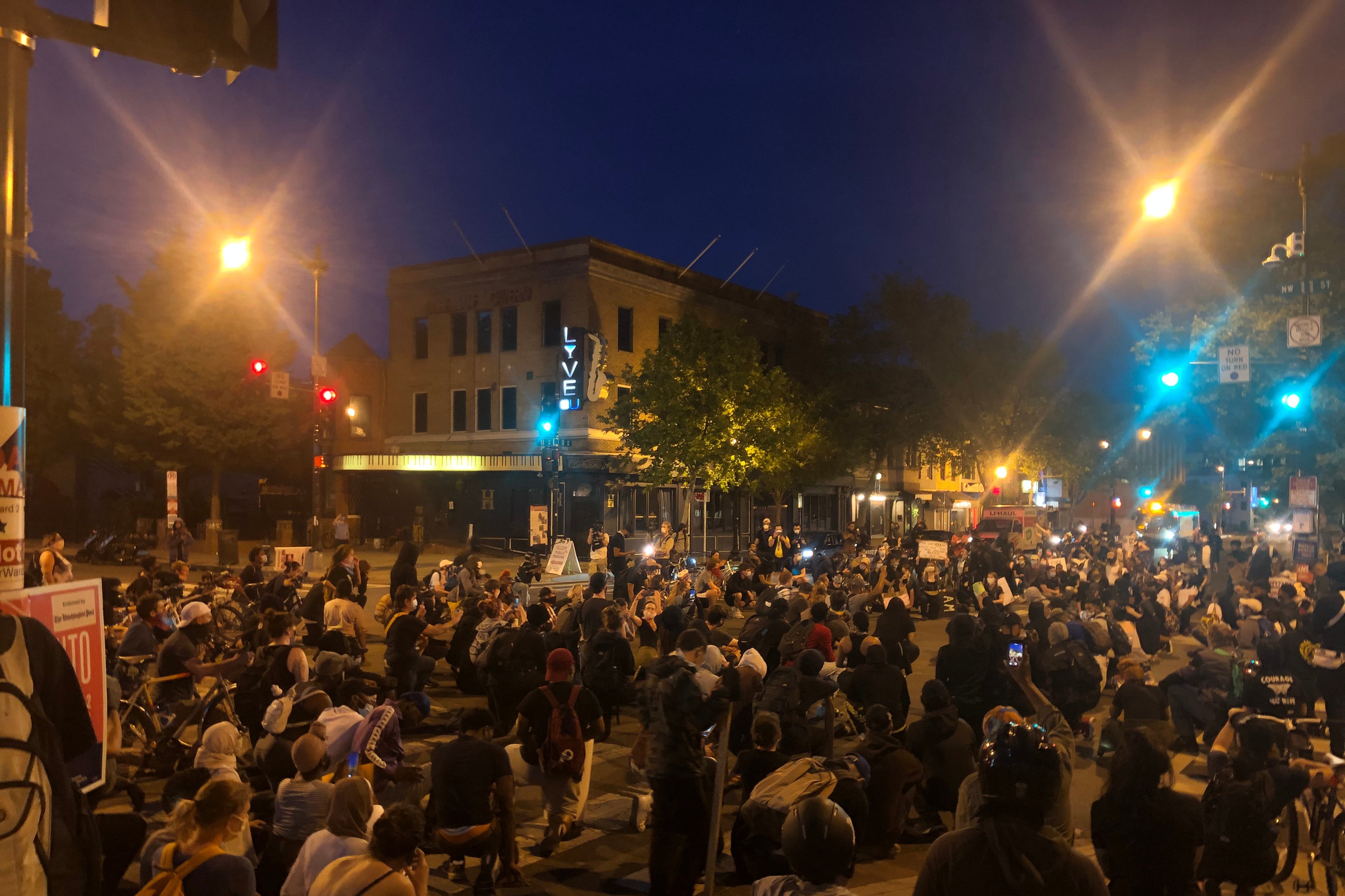 A large crowd of protestors kneel at an intersection in D.C.