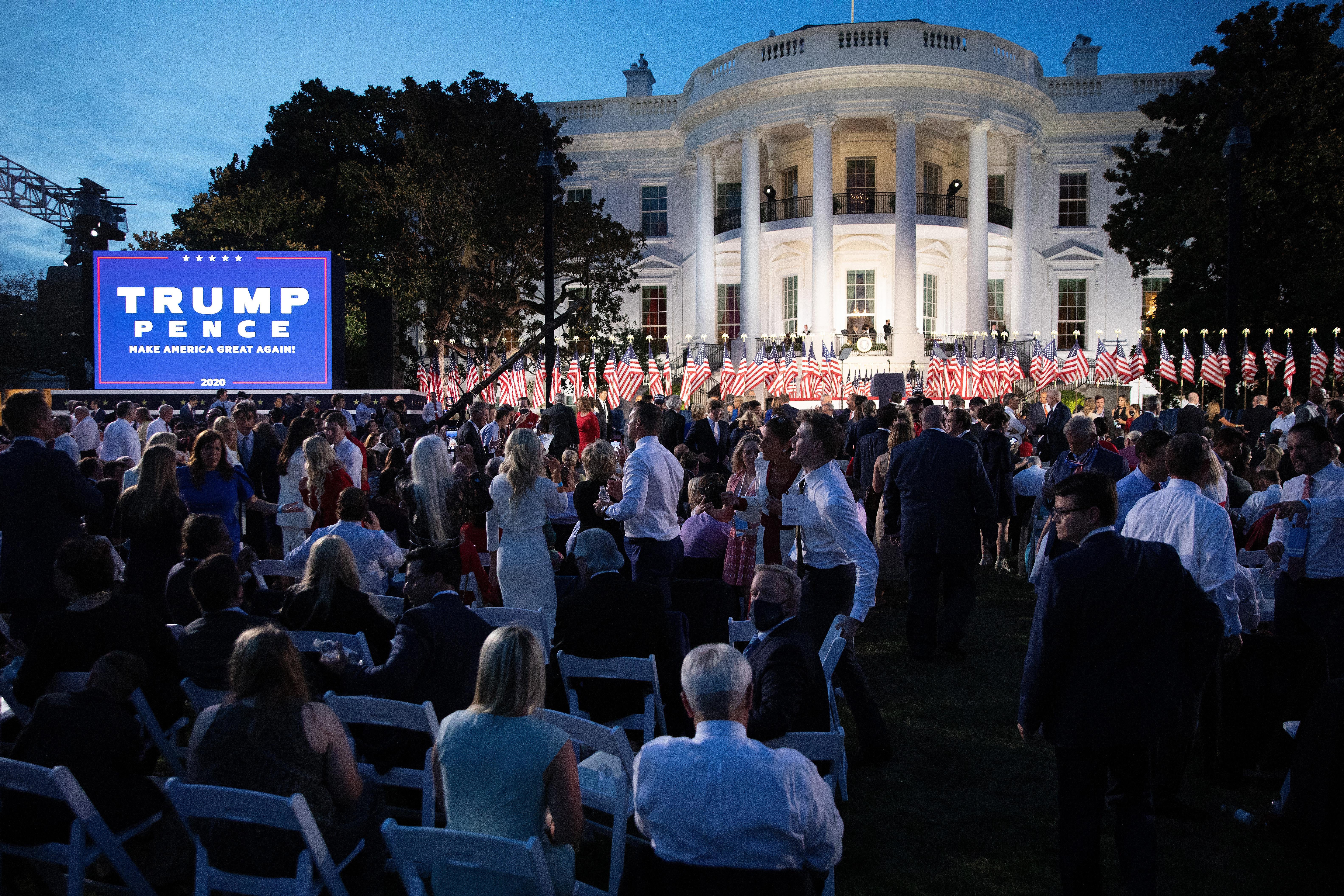 The south lawn of the White House, filled with people overshadowed by a giant Trump Pence sign.