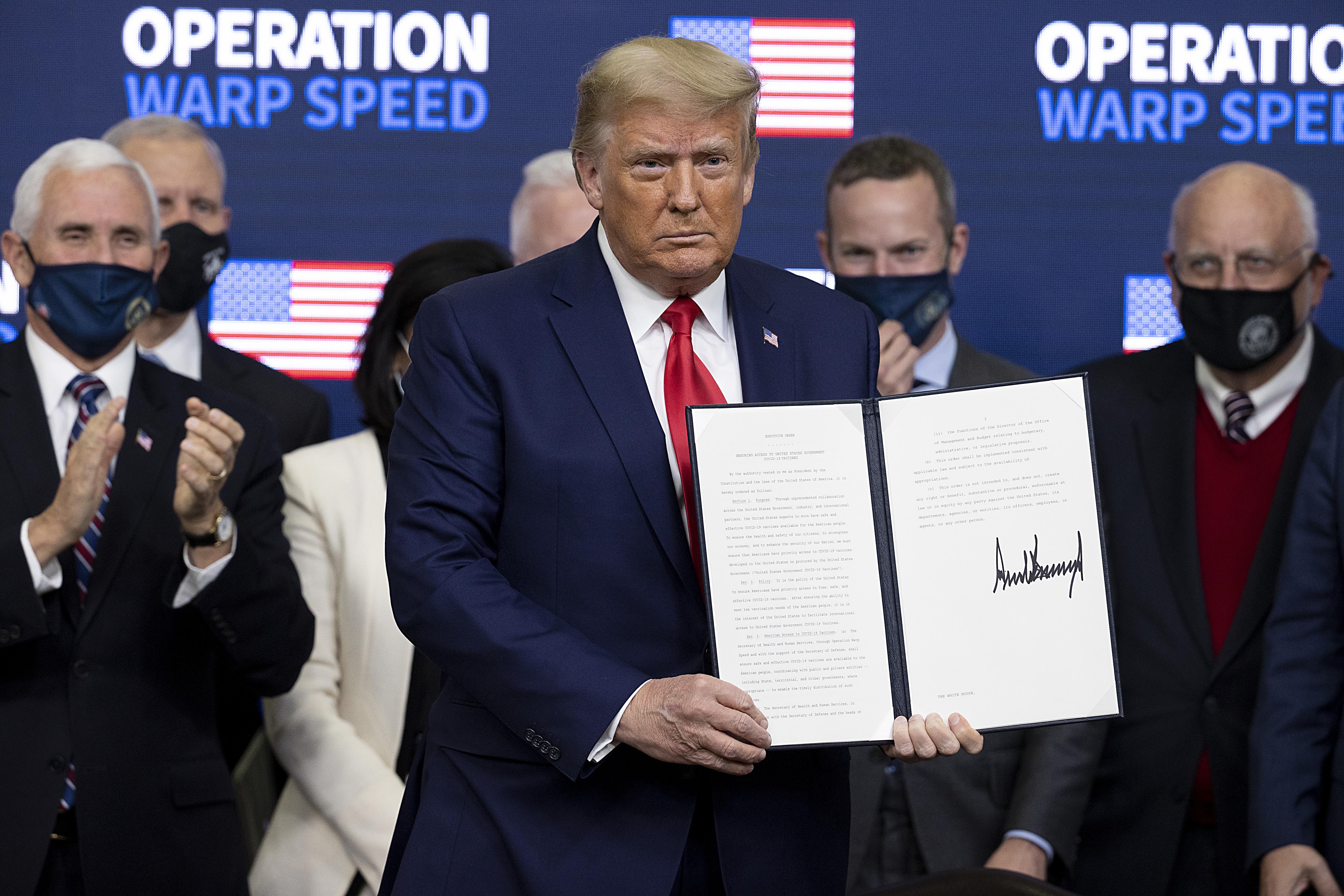 Trump holds up a bill with his signature.