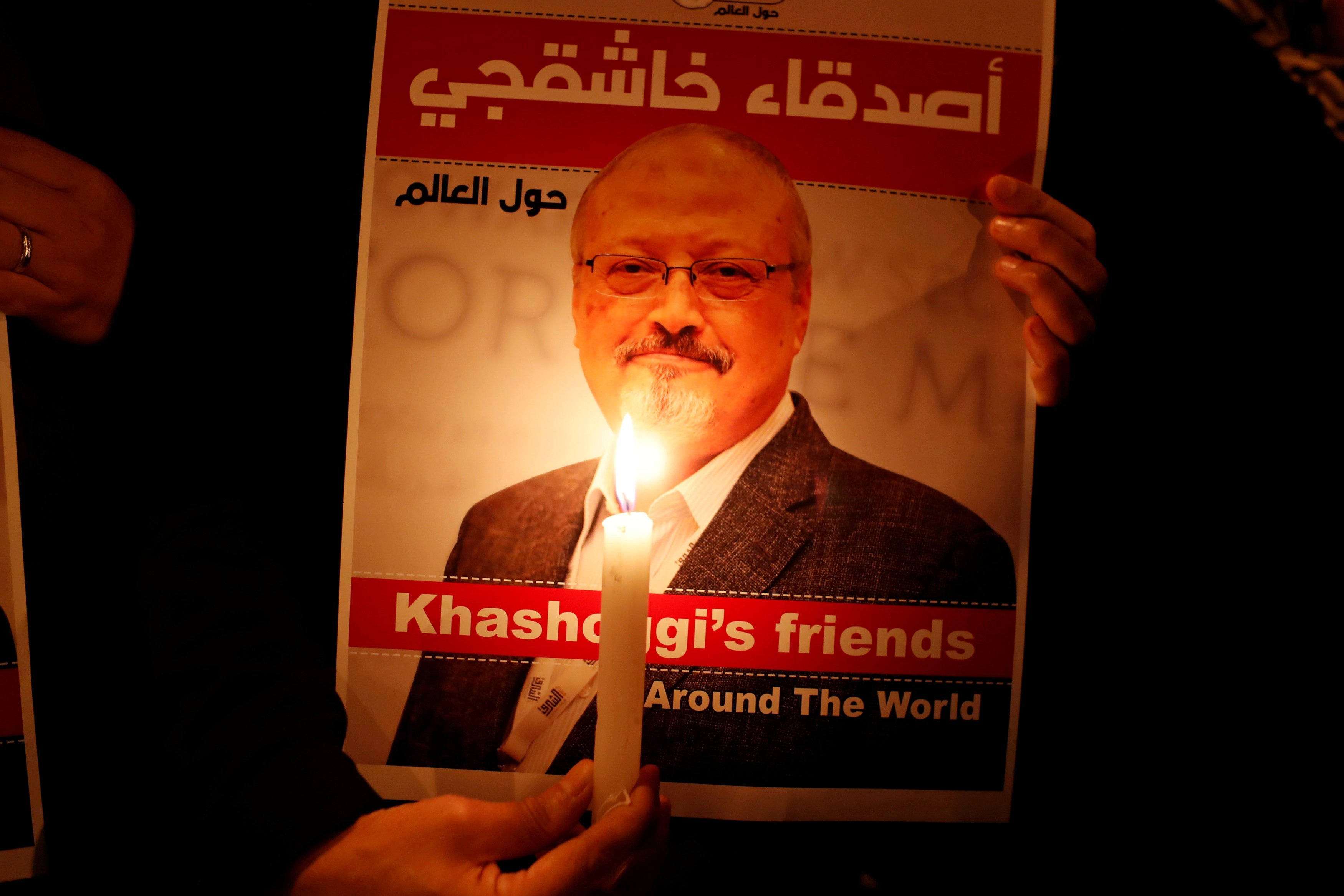A demonstrator holds a candle in front of a poster with a picture of Saudi journalist Jamal Khashoggi.