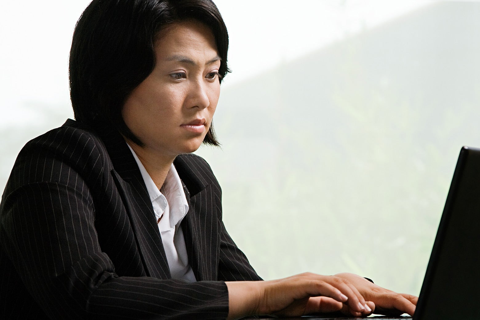 A woman staring at a laptop with glazed eyes.