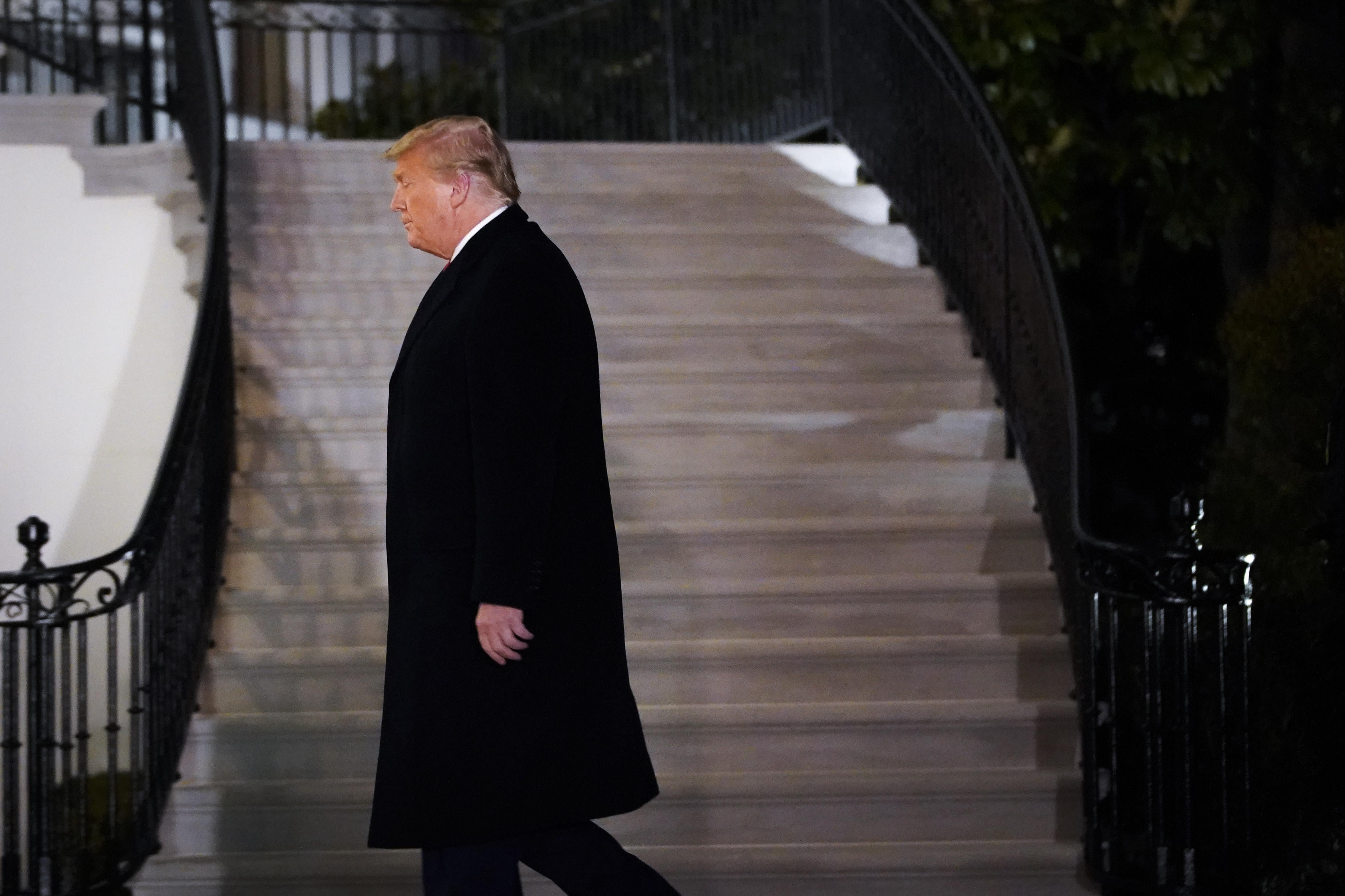 Trump in profile as he walks to the White House residence at night