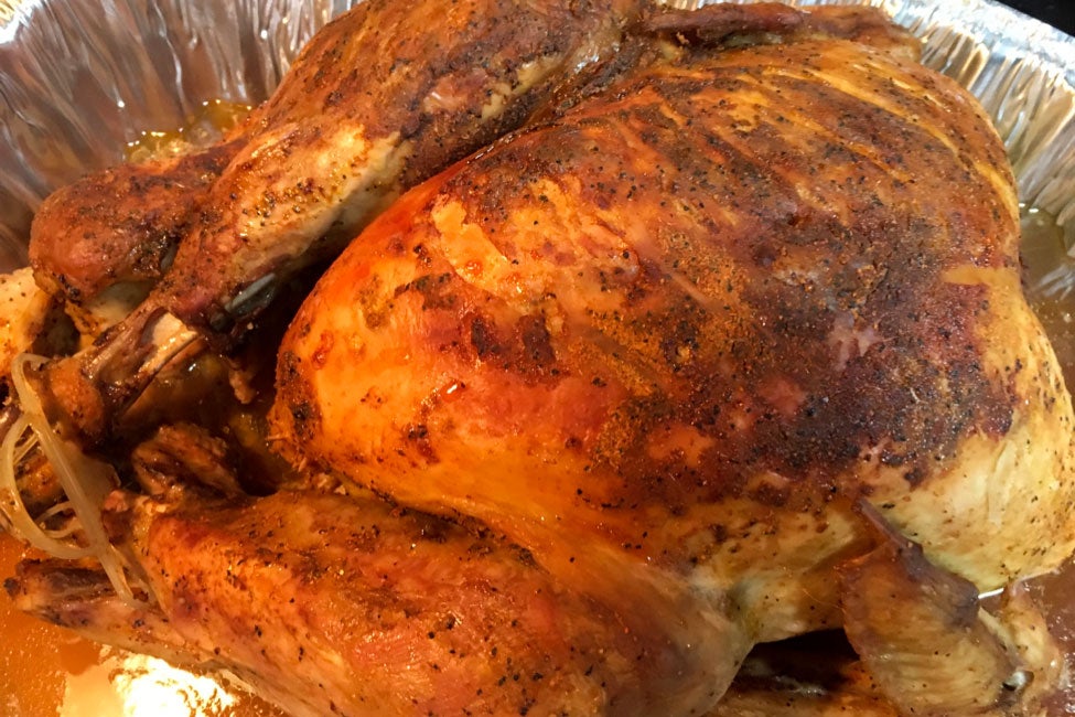 A golden-brown turkey in a foil roasting pan.