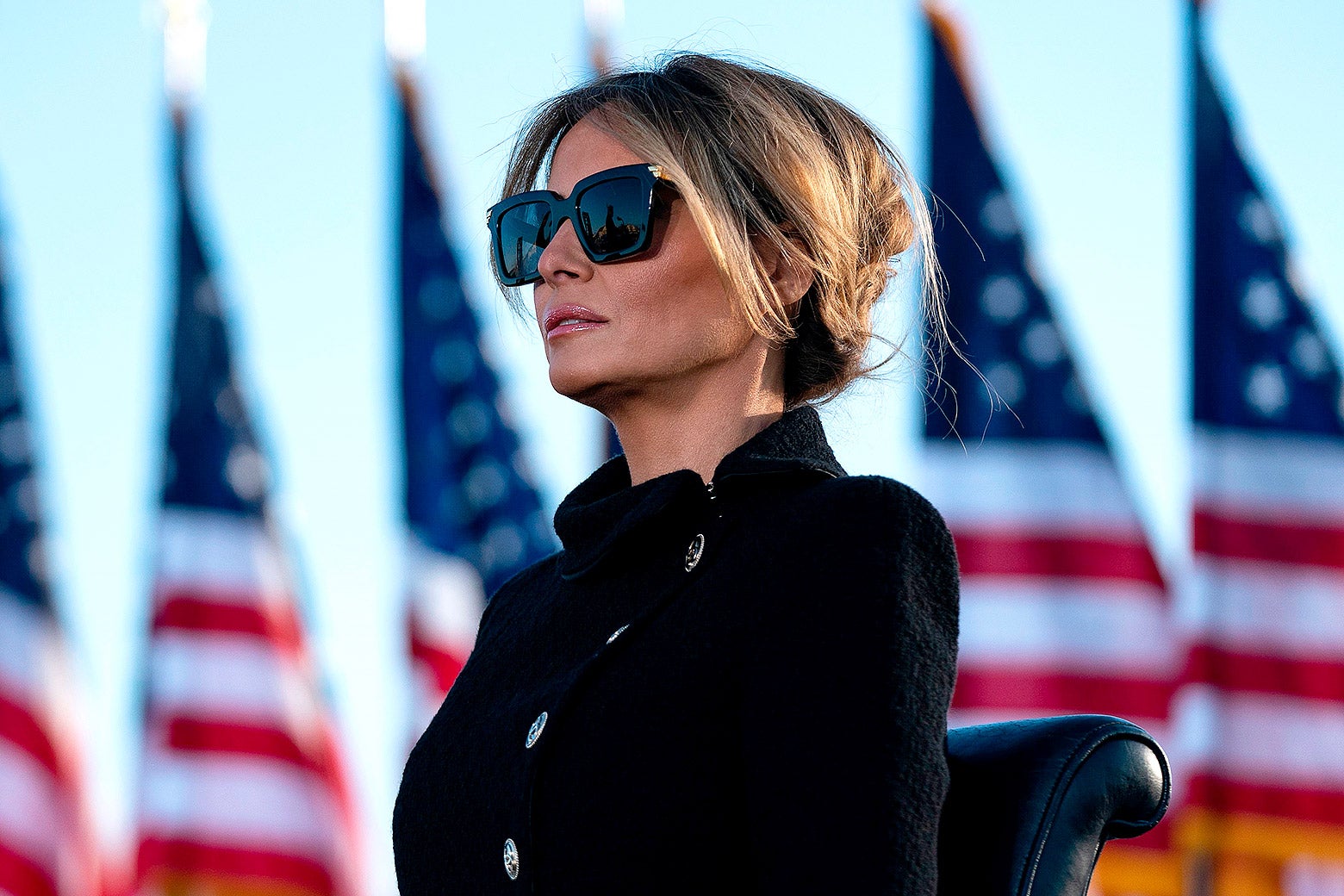Melania Trump wearing dark large sunglasses stares straight ahead. 