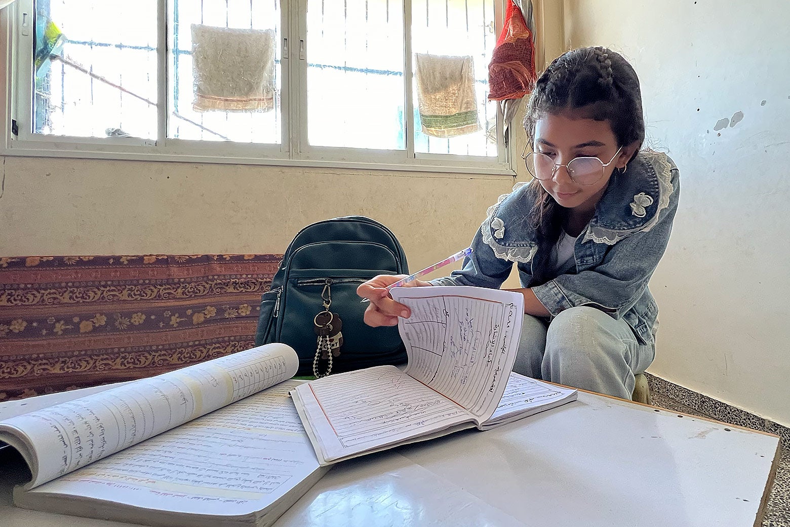 A middle-school-aged girl pages through a workbook at a low table. 