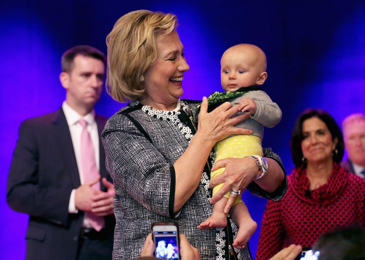 Former Secretary of State Hillary Clinton holds a baby