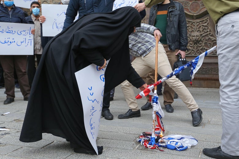 Students of Iran's Basij paramilitary force burn US and Israeli flags during a rally in front of the foreign ministry in Tehran, on November 28, 2020, to protest the killing of prominent nuclear scientist Mohsen Fakhrizadeh a day earlier near the capital.