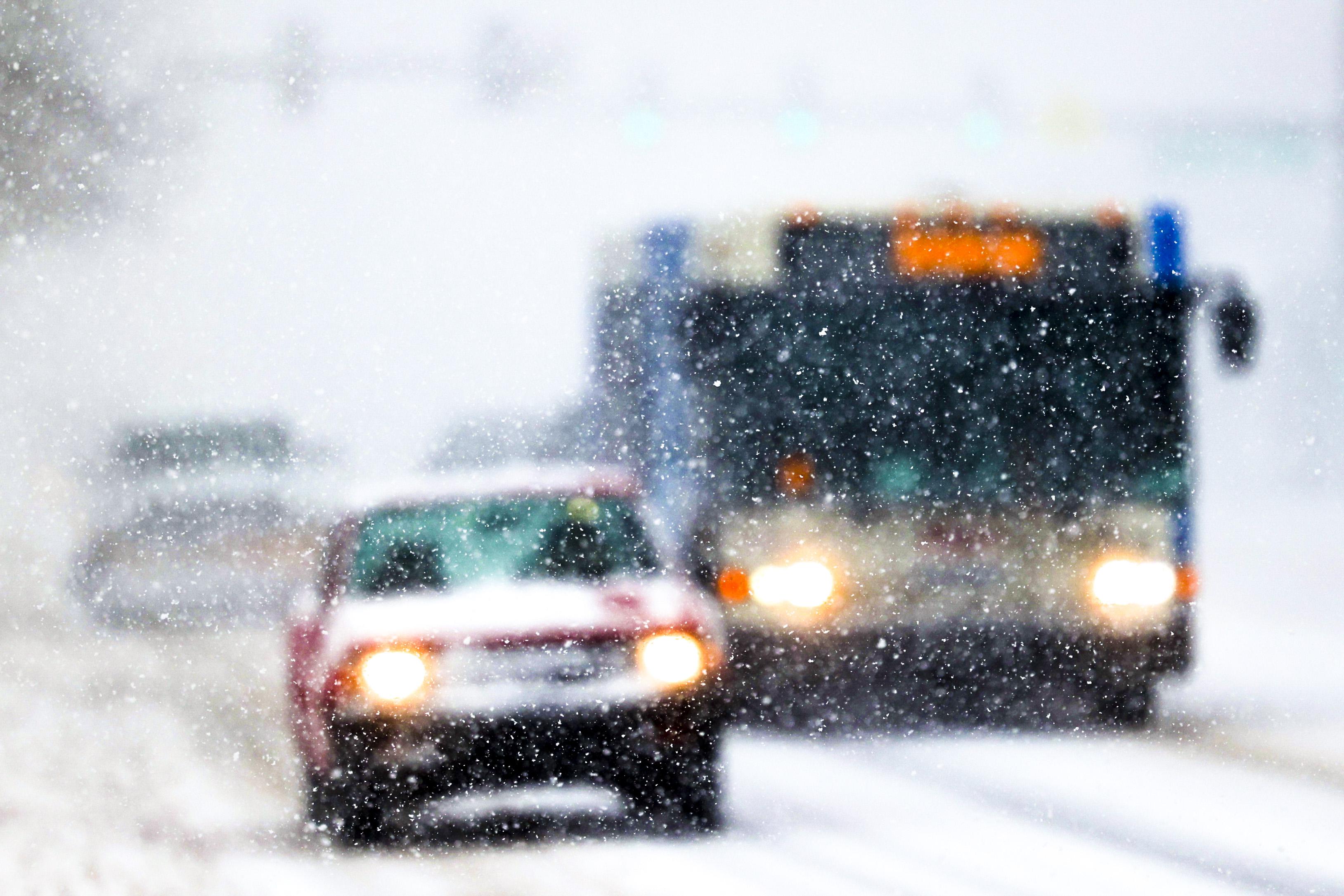 Cars and a bus drive through snow on Colfax Avenue in Denver