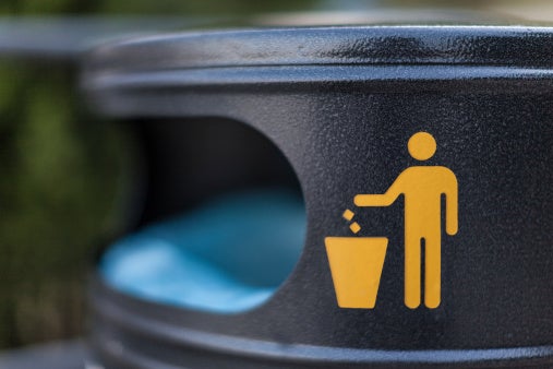 An outdoor garbage can with a graphic depicting a person throwing something in it.