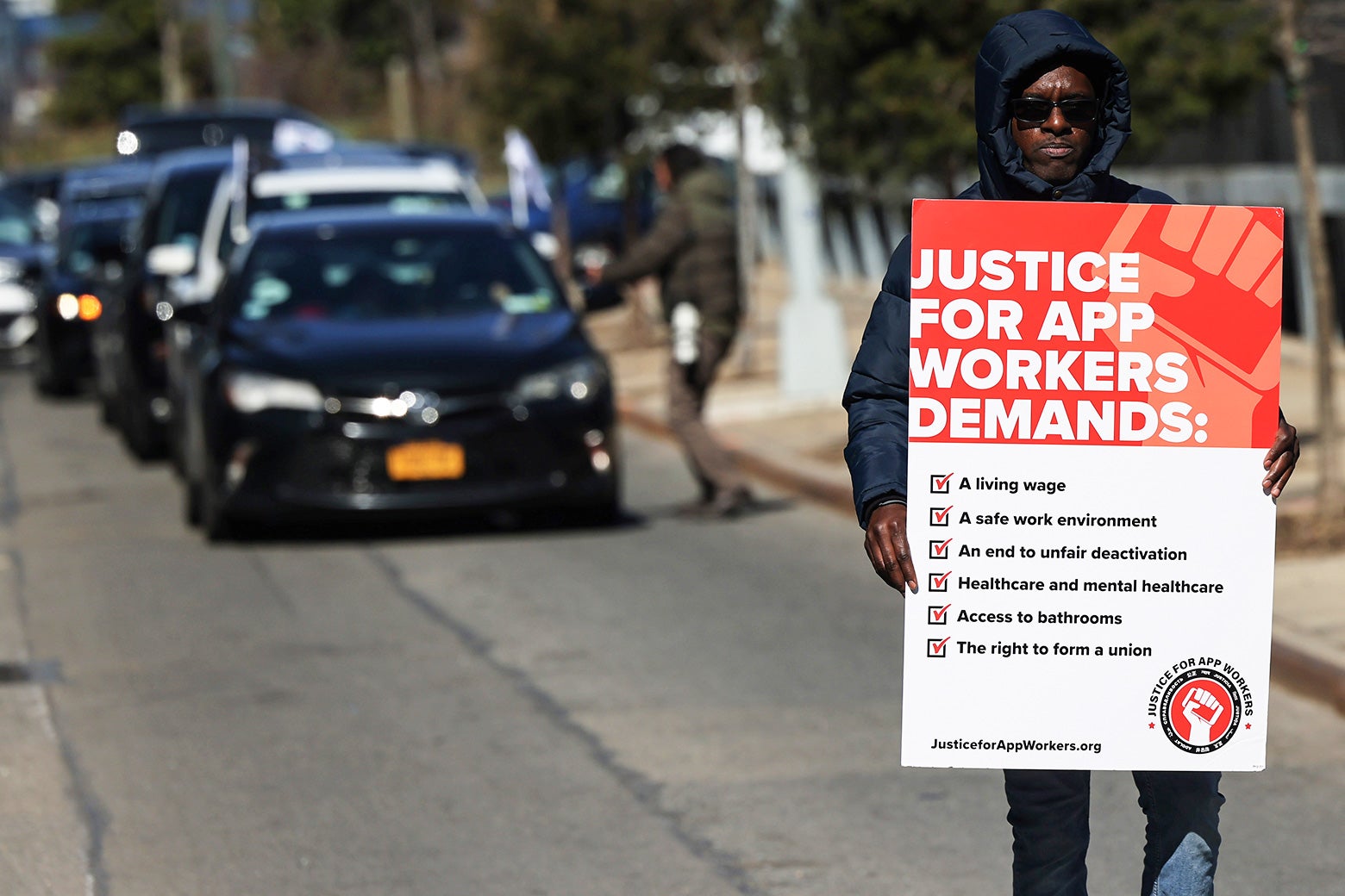 An Uber and Lyft driver walks as he carries a sign as he joins other app-based drivers and delivery workers take part in a protest at the former headquarters of Uber Technologies in New York in 2022.