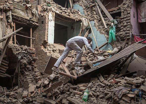 A man climbs on top of debris after buildings collapsed on April 26, 2015 in Bhaktapur, Nepal.