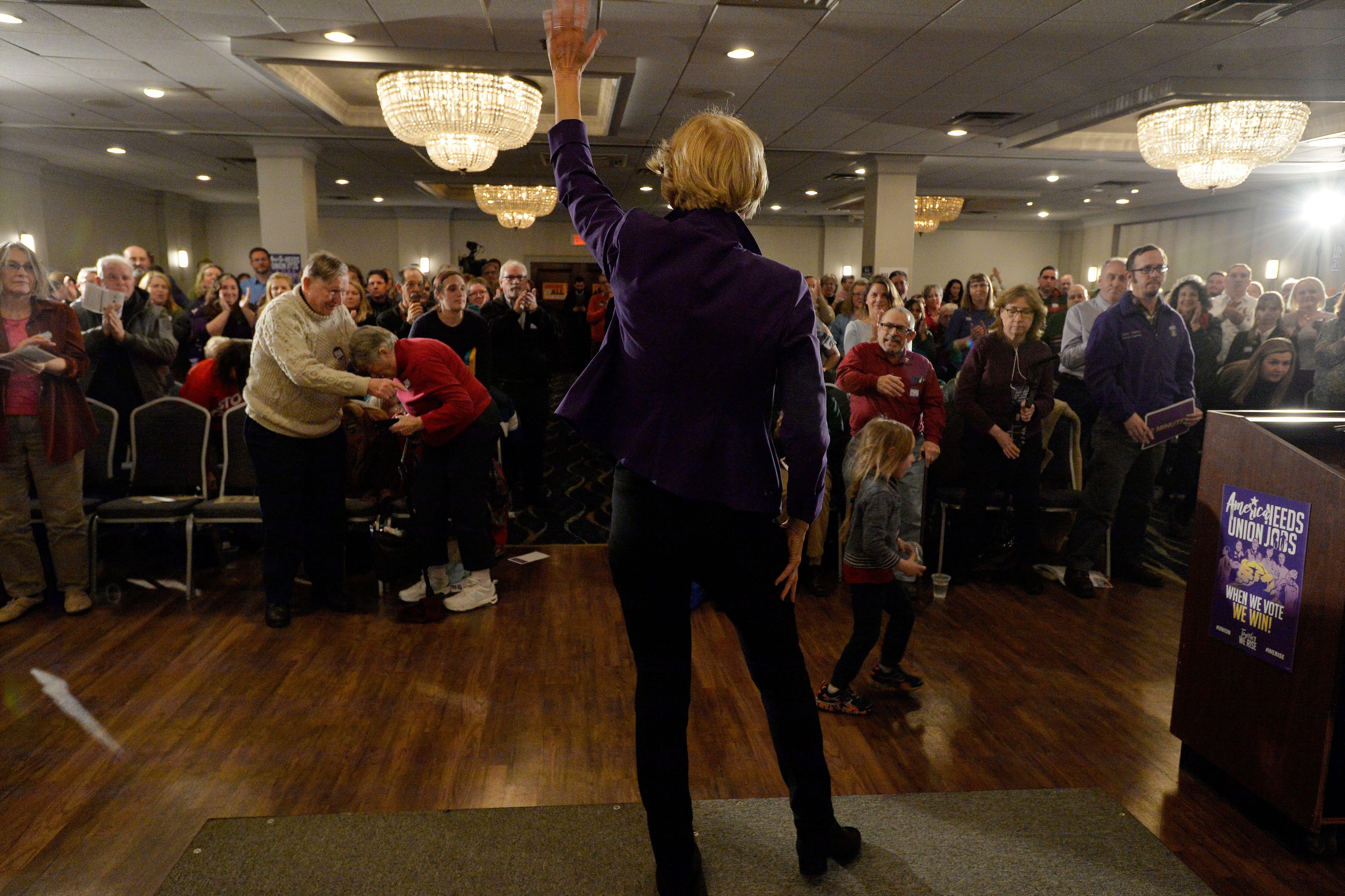 Elizabeth Warren seen from the back as she waves to a crowd of members of SEA/SEIU Local 1984, state employees, at the Holiday Inn in Concord, New Hampshire.