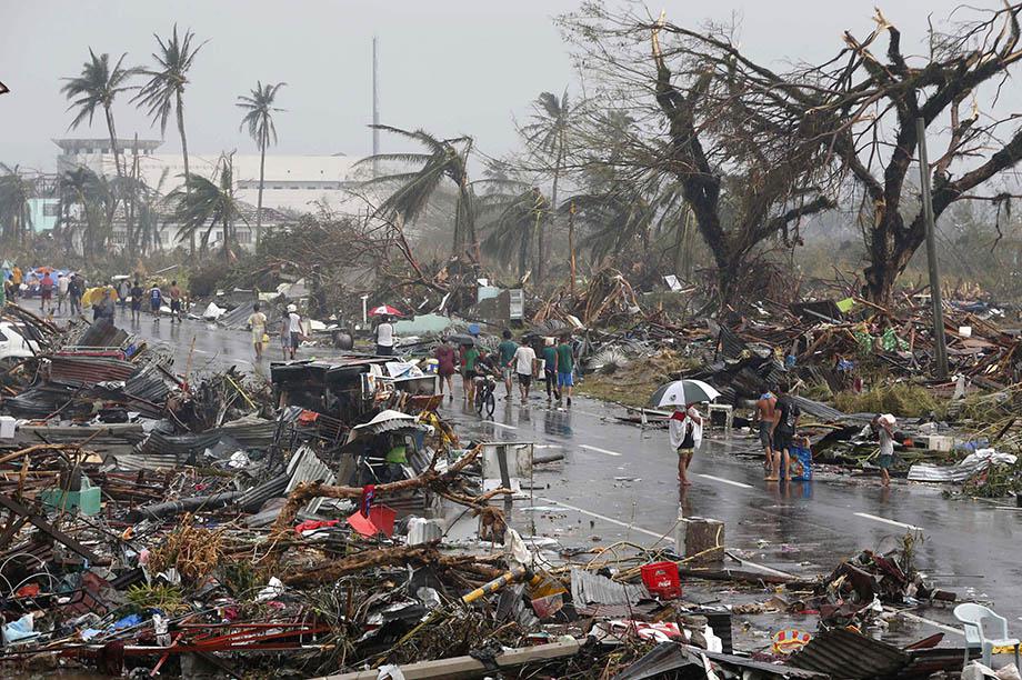 Residents walk on a road littered with debris after Super Typhoon Haiyan battered Tacloban city in central Philippines November 10, 2013.