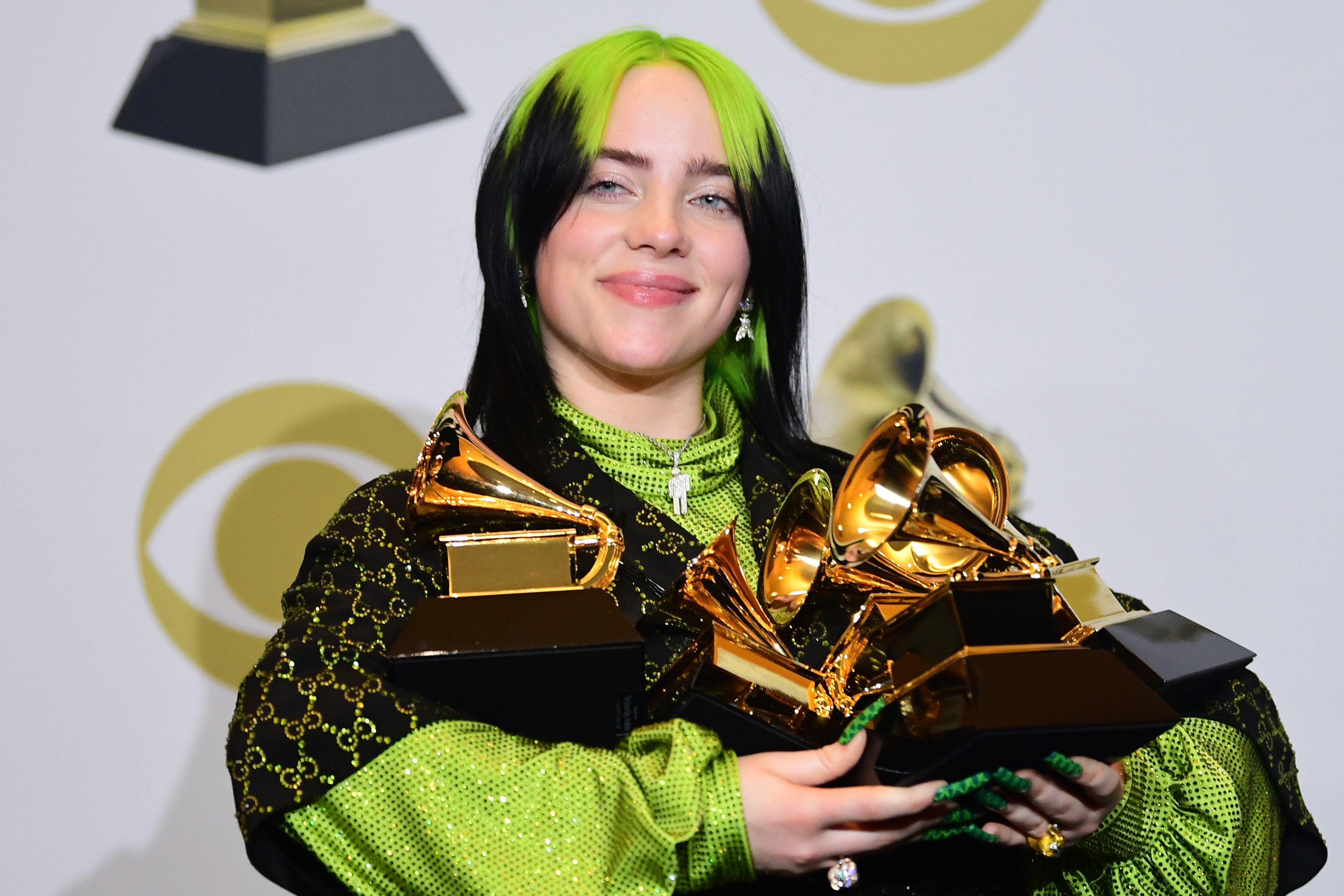 Billie Eilish carries an armful of Grammy trophies.