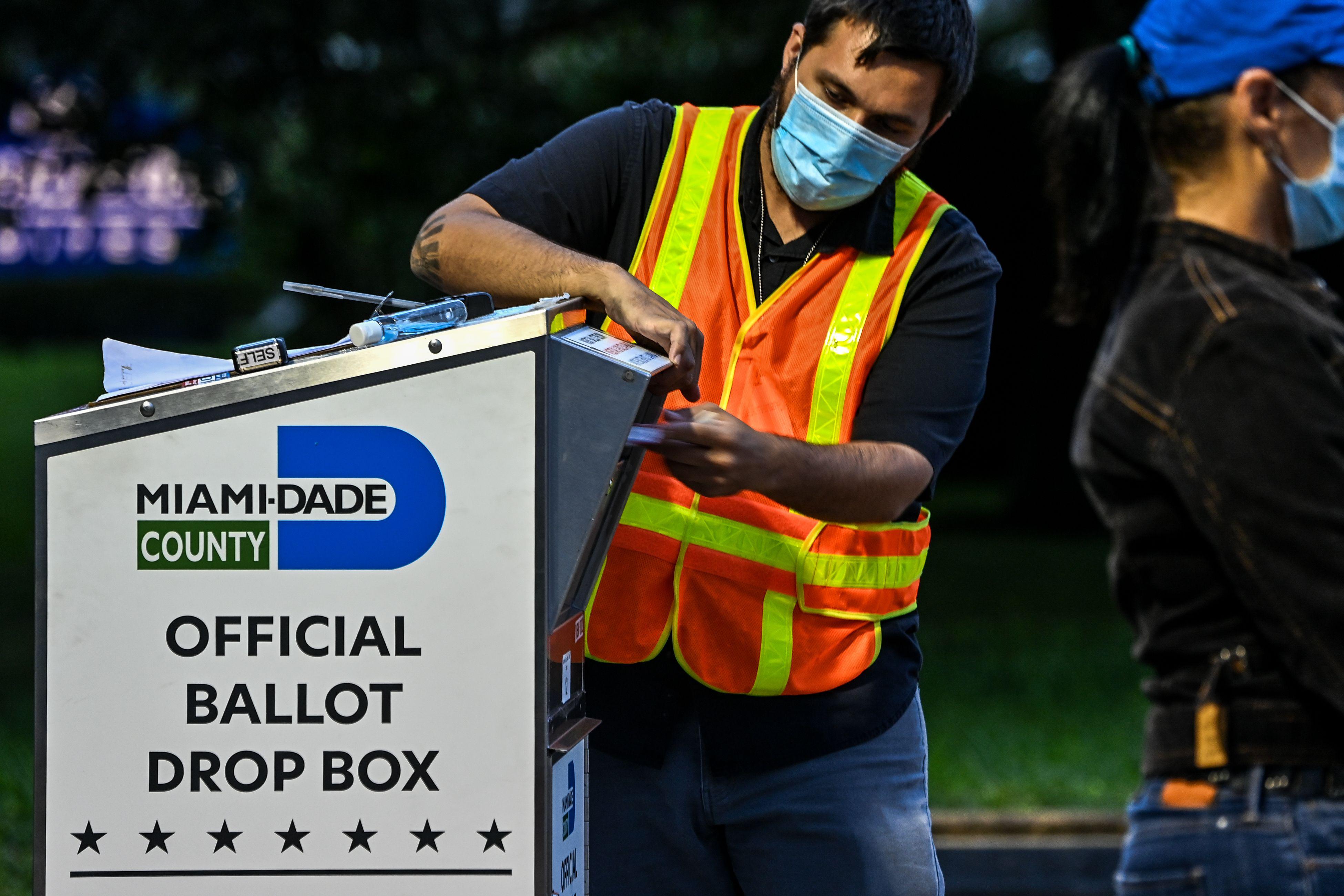 A man puts a ballot in a drop box
