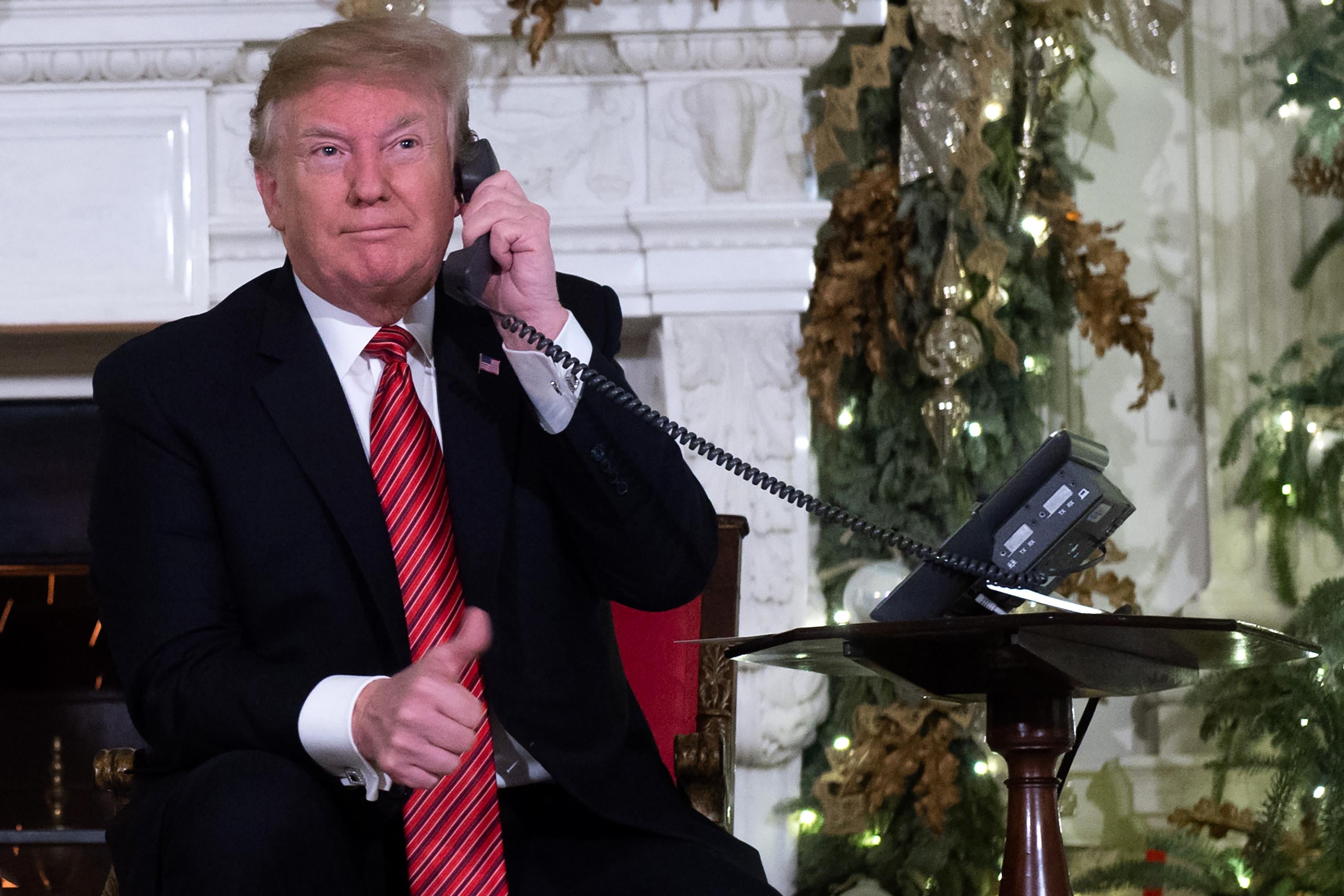 President Donald Trump speaks on the telephone as he answers calls from people calling into the NORAD Santa tracker phone line in the State Dining Room of the White House in Washington, D.C. on December 24, 2018. 