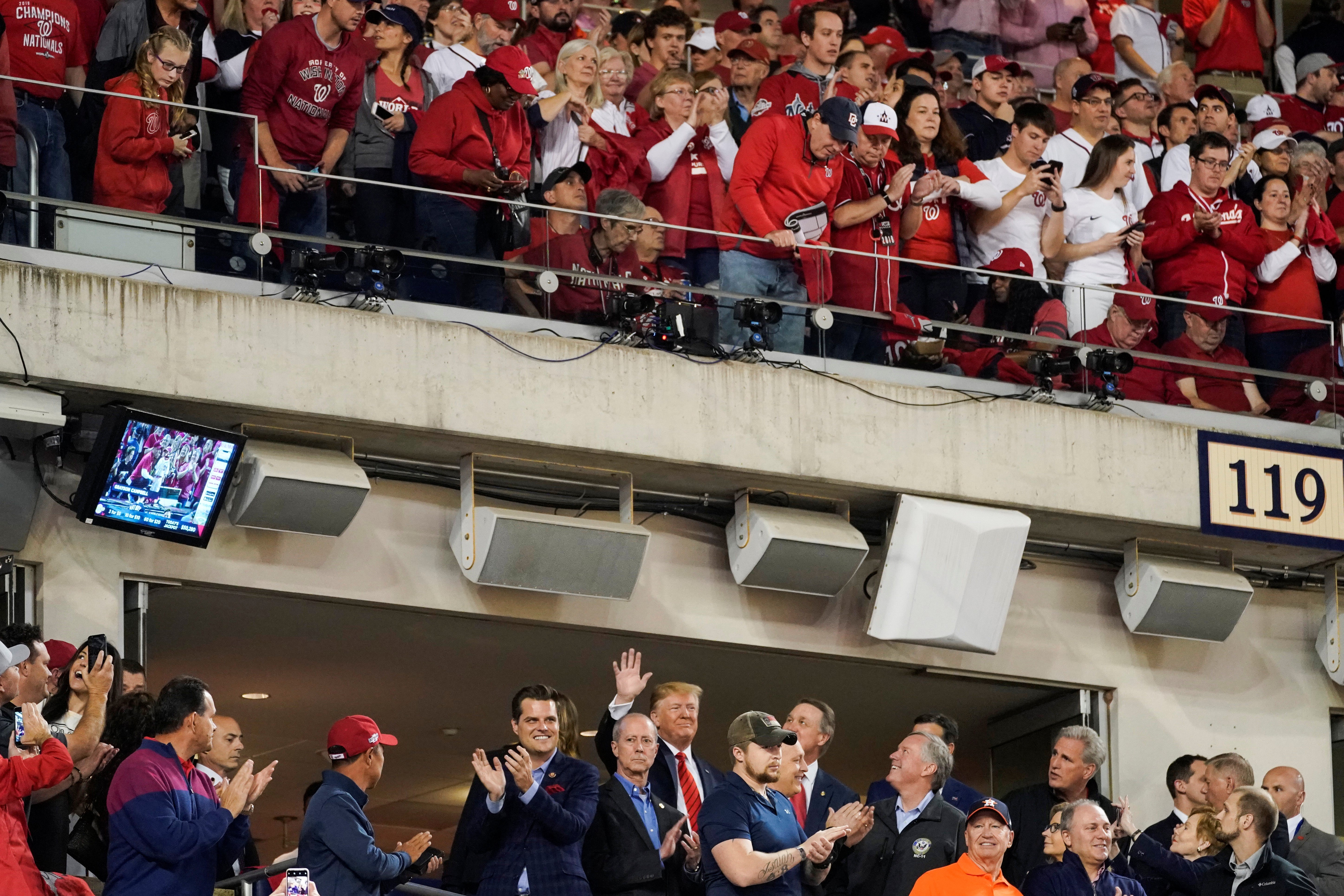 Trump waves from a luxury box above which fans can be seen in the upper deck.