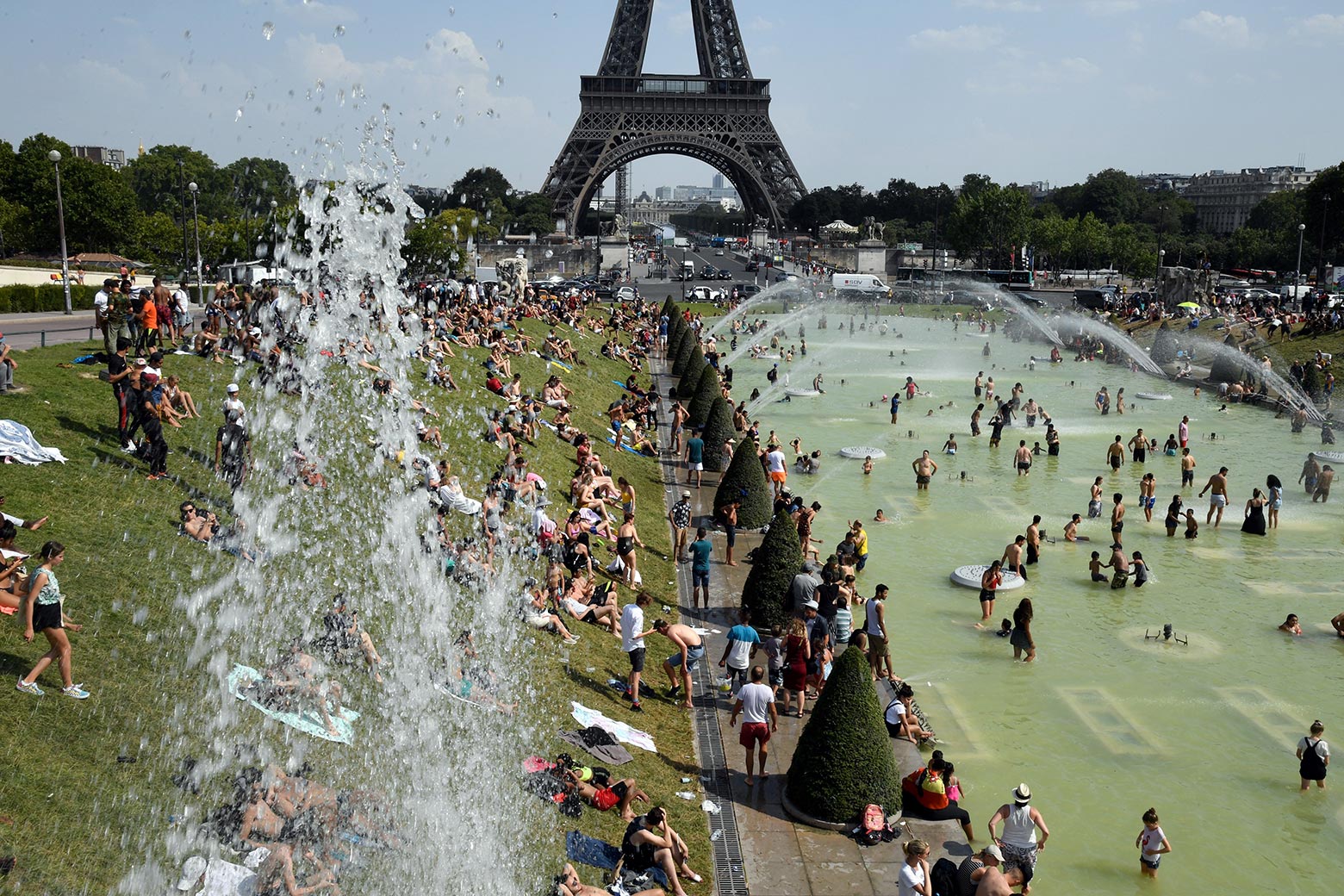 People cool off and sunbathe by the Trocadéro fountains next to the Eiffel Tower in Paris on Thursday.
