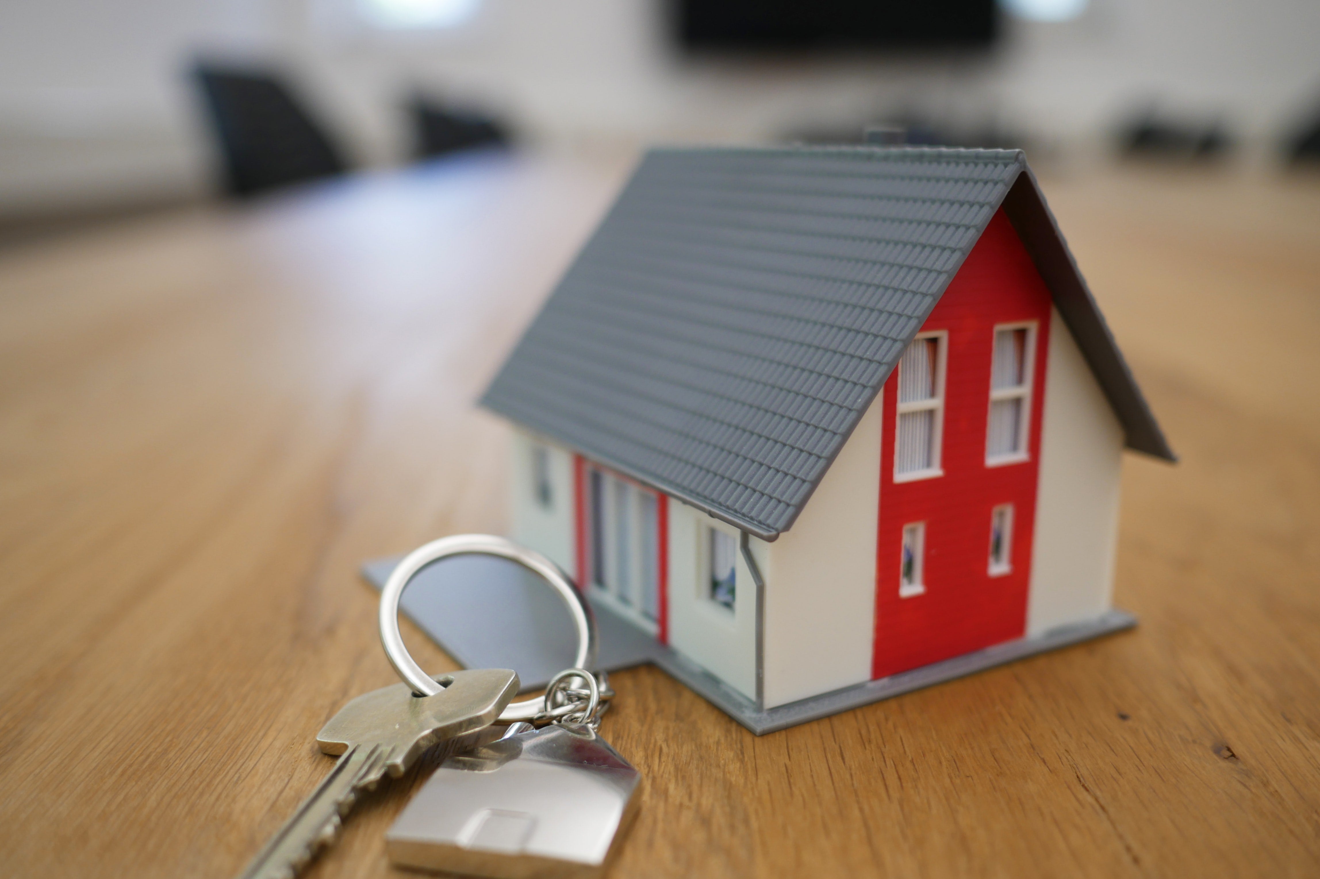 A keychain with a key on it next to a small model of a house.