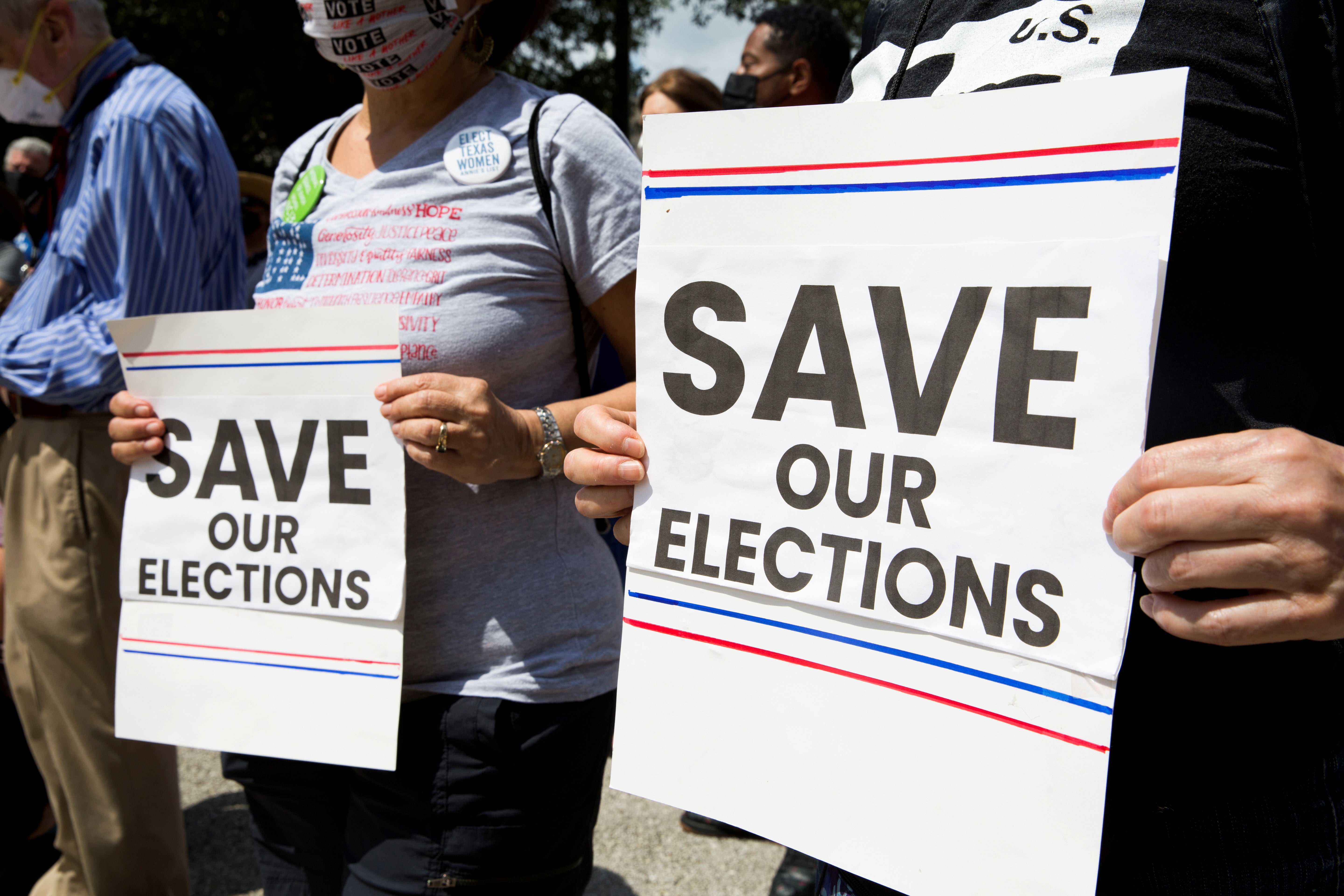 Two people hold up signs that say "Save Our Elections."