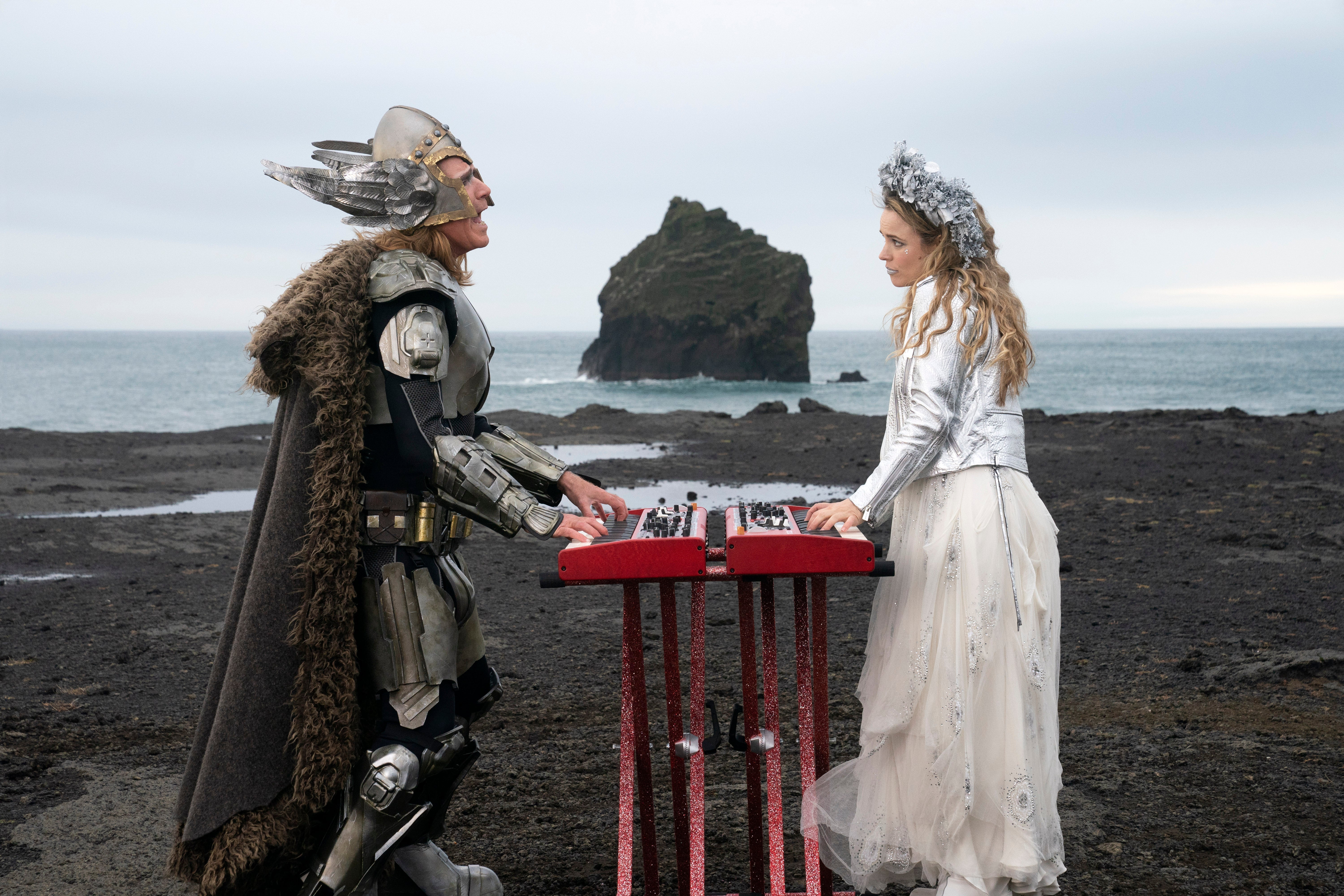 Will Ferrell, in Viking helmet, and Rachel McAdams, in jeweled tiara, play keyboards on the rocks by the ocean.