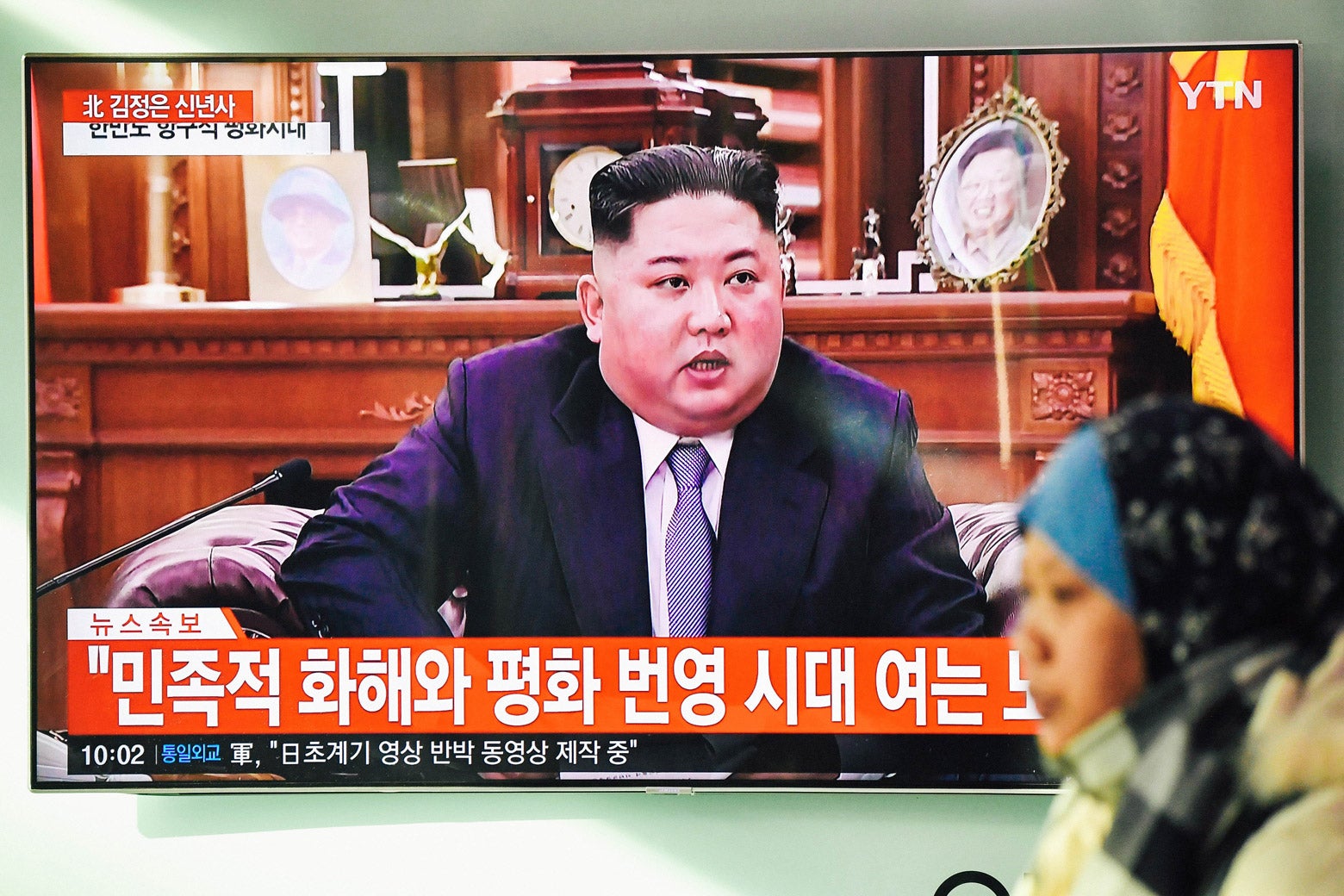 A woman walks past a television screen showing North Korean leader Kim Jong-un giving a New Year’s speech.
