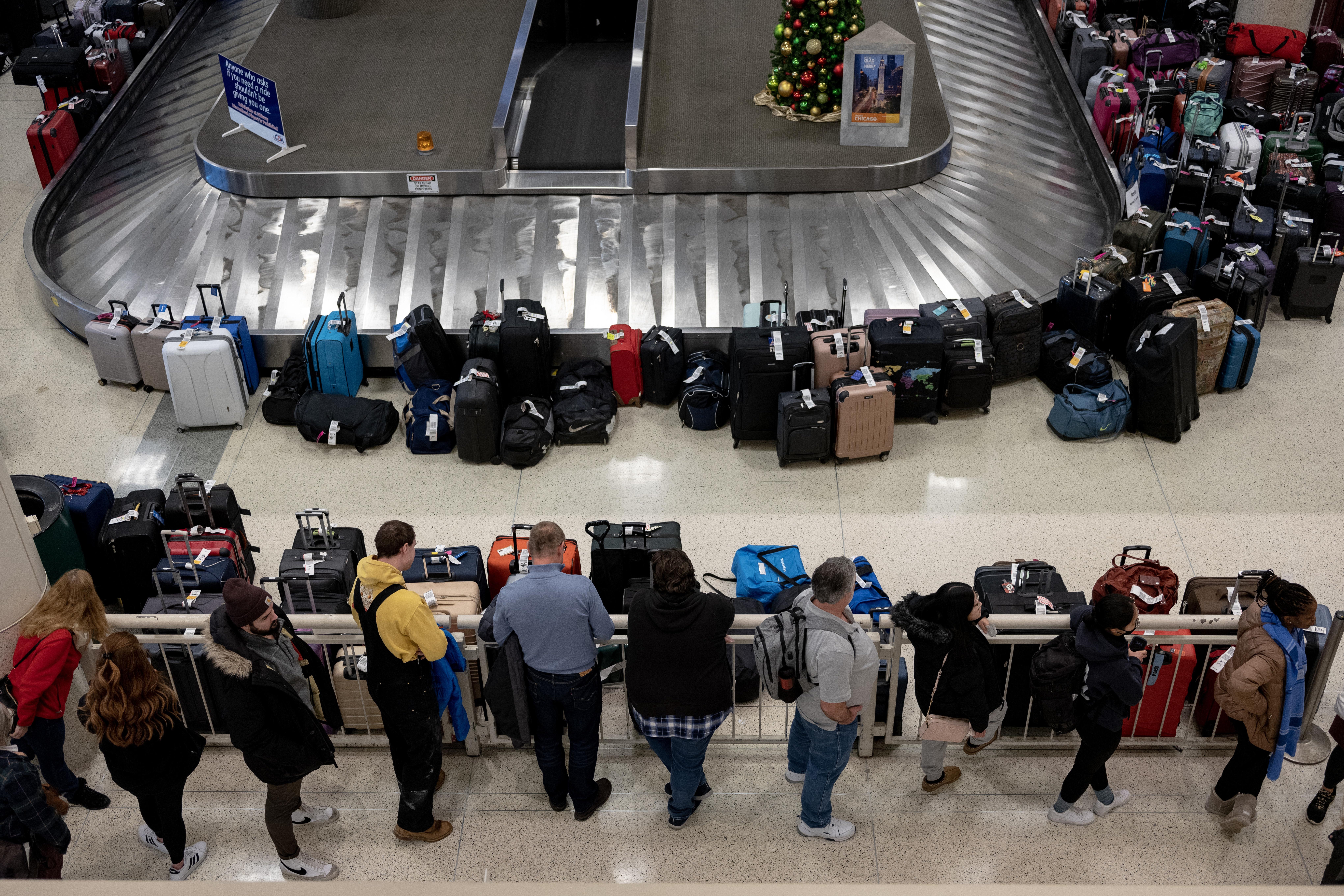 An aerial shot of customers lined up in front of a blocked off baggage claim band surrounded by luggage.
