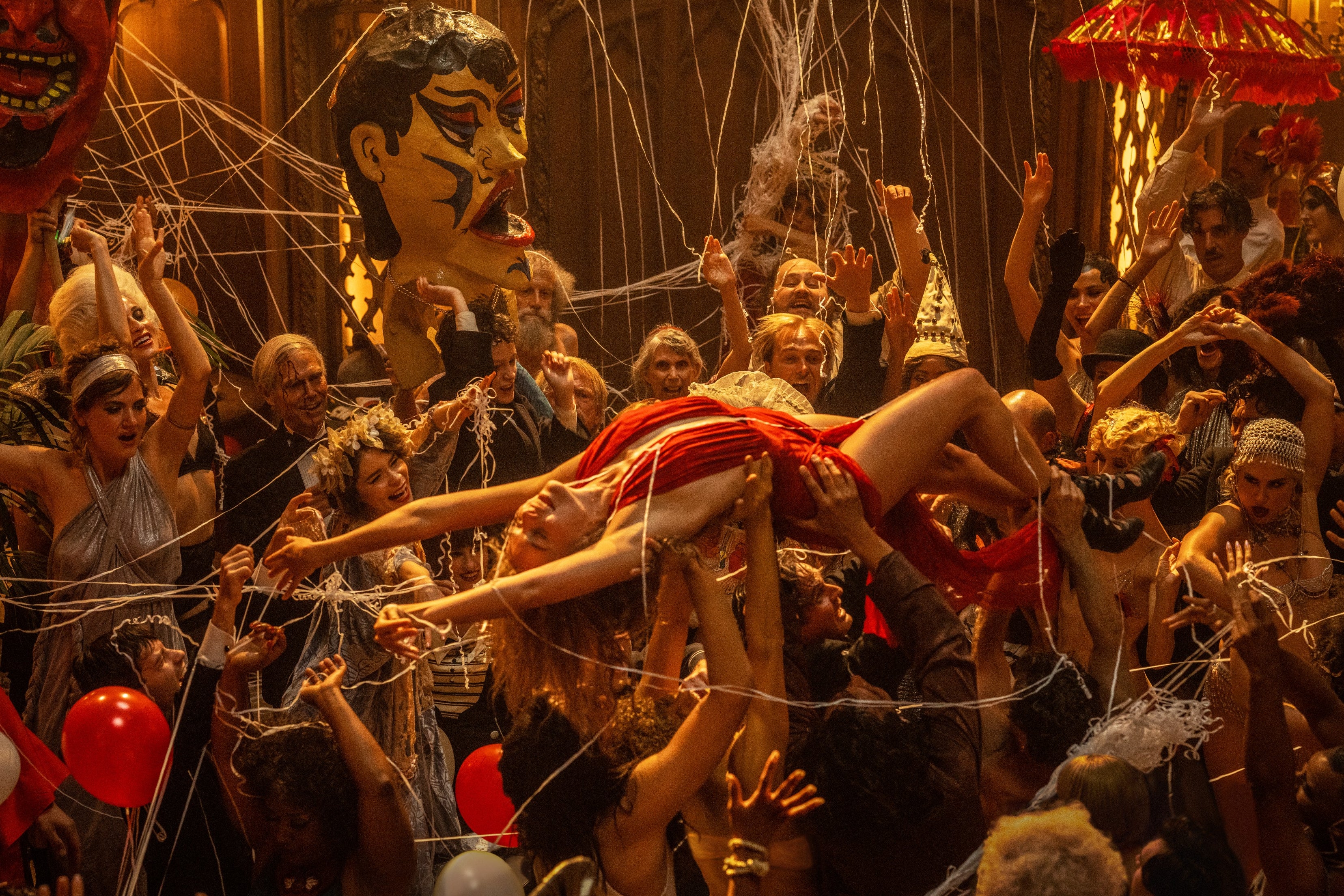 Margot Robbie lies back ecstatic in a barely-there red dress as she crowdsurfs on a crowd full of debaucherous 1920s partygoers
