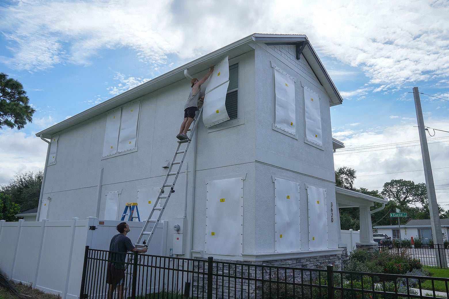 A homeowner is on a ladder to covers the top-floor windows of his house in Tampa, Florida.