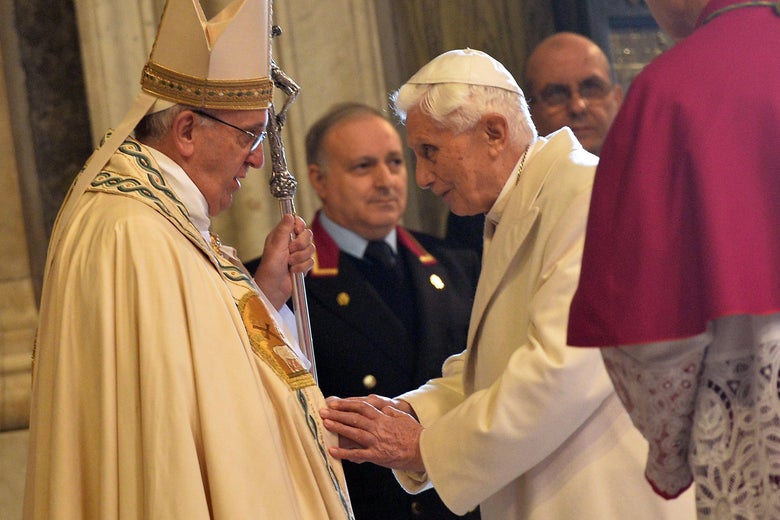 The two popes lean toward each other to speak.