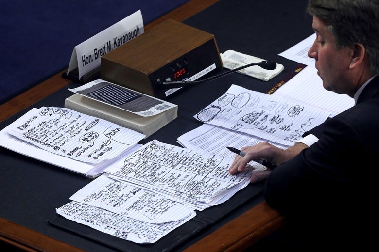 Brett Kavanaugh looks at his notes at a table in a hearing room.