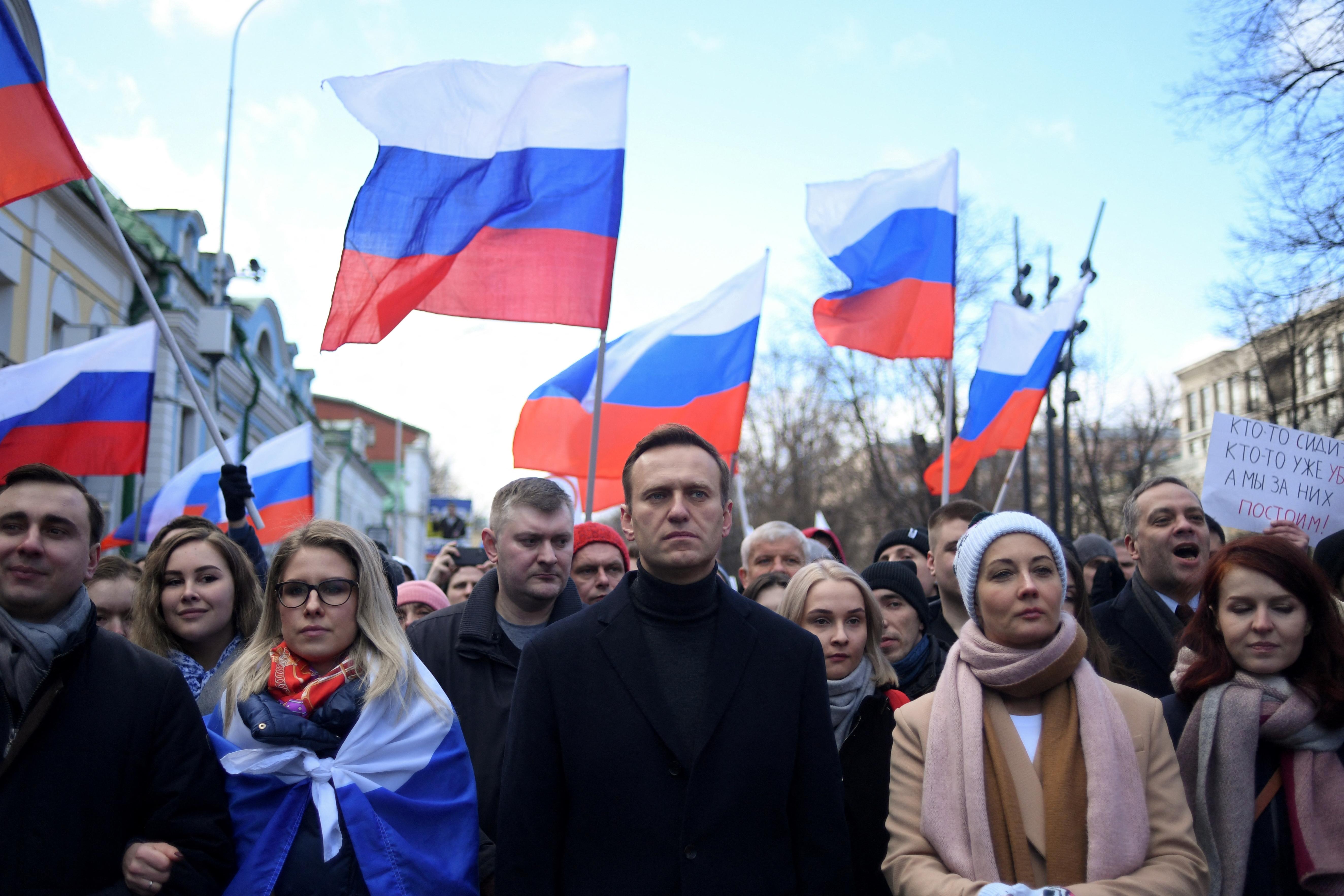 A crowd of people marching, with Russian flags waving above their heads.