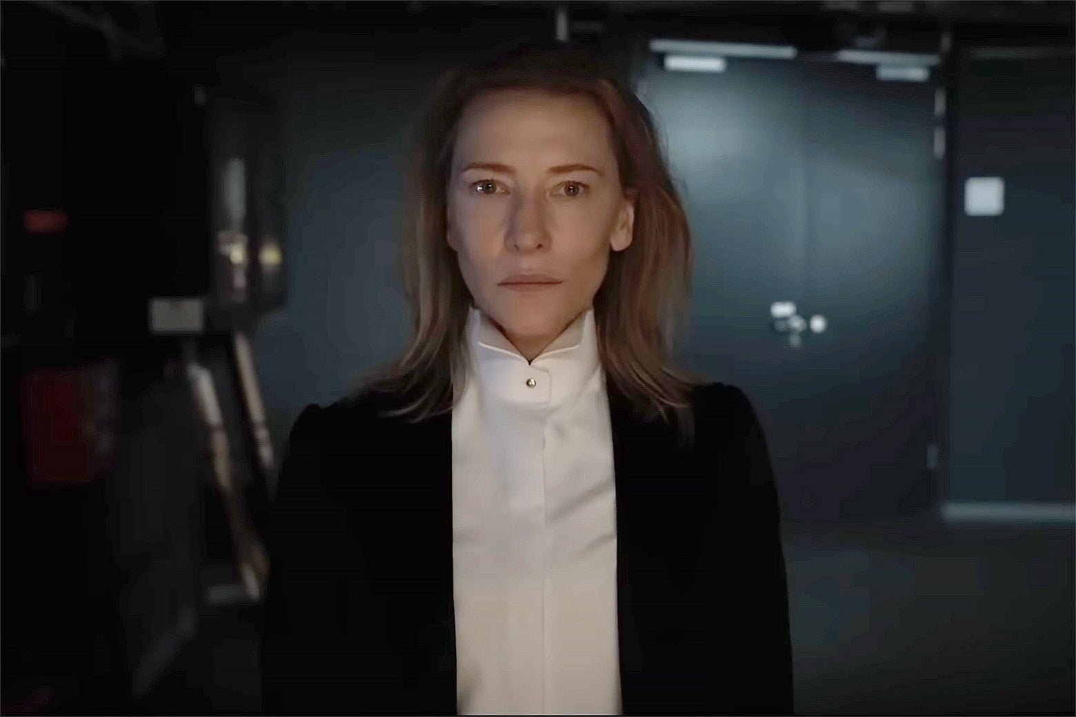 Cate Blanchett, as Lydia Tár, wears a conductor's suit and stares into the camera.