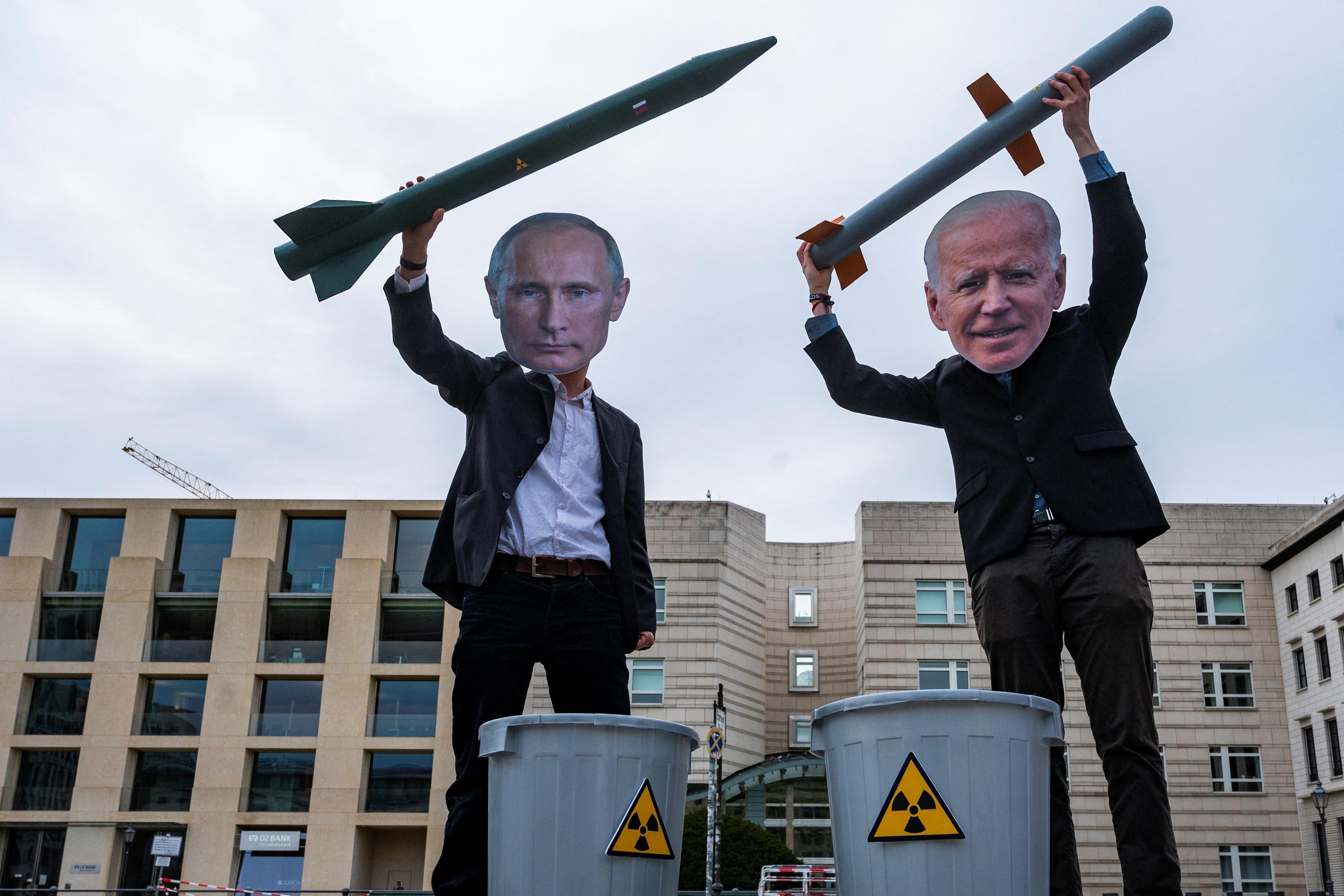 Peace activists wearing masks of Russian President Vladimir Putin (L) and newly elected US President Joe Biden pose with mock nuclear missiles in front of the US embassy in Berlin on January 29, 2021 in an action to call for more progress in nuclear disarmament. - The Russian parliament on January 27, 2021 unanimously voted to ratify an agreement to extend by five years a key nuclear pact with the United States that was set to expire soon. Signed in 2010, the New START contract caps to 1,550 the number of nuclear warheads that can be deployed by Moscow and Washington, which control the world's largest nuclear arsenals. The agreement, which was due to expire on February 5, is seen as a rare opportunity for compromise between Moscow and Washington, whose ties have dramatically deteriorated in recent years. (Photo by John MACDOUGALL / AFP) (Photo by JOHN MACDOUGALL/AFP via Getty Images)