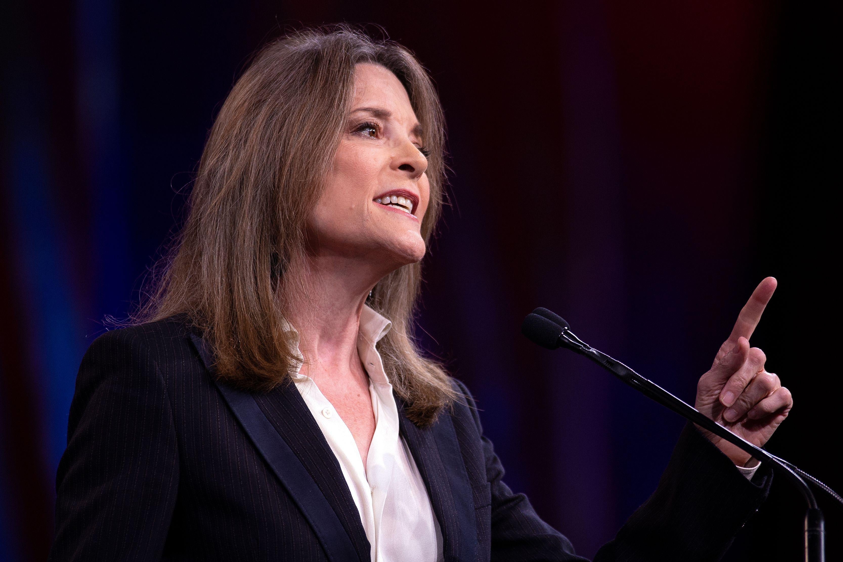 Marianne Williamson points a finger while speaking at a podium.