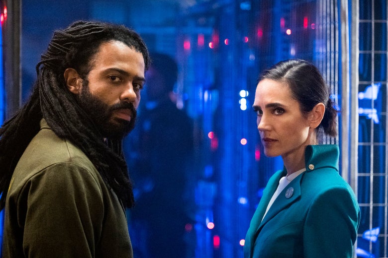 Daveed Diggs and Jennifer Connelly in Snowpiercer, with Diggs wearing a futuristic workshirt and Connelly wearing a futuristic power suit.