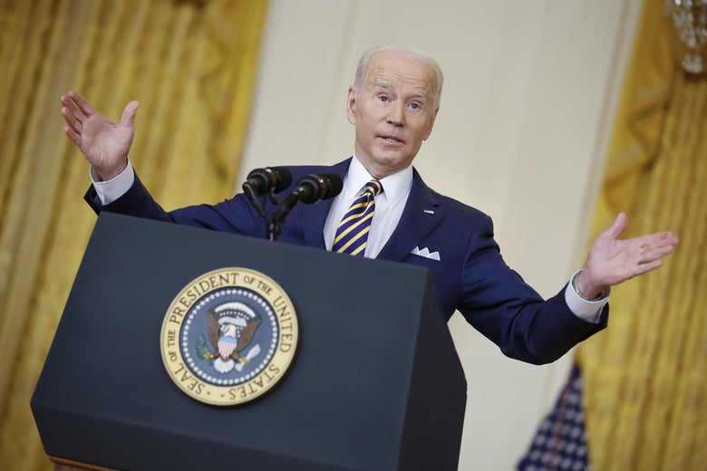 Biden raising both arms as he speaks at a podium