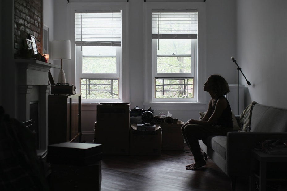 A woman sits alone in an apartment with music equipment