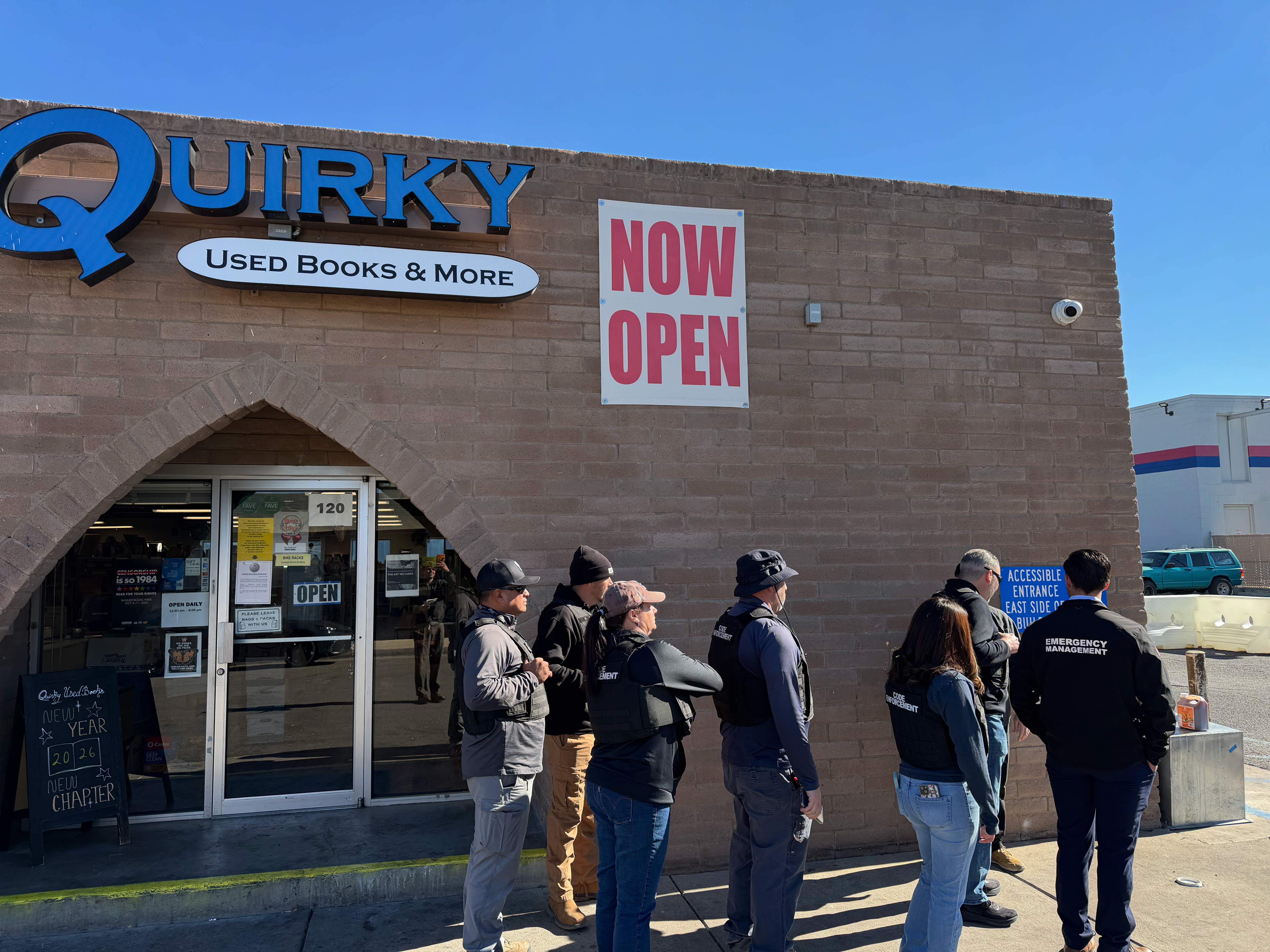 A group of people stand surveying the outside of the bookstore. 