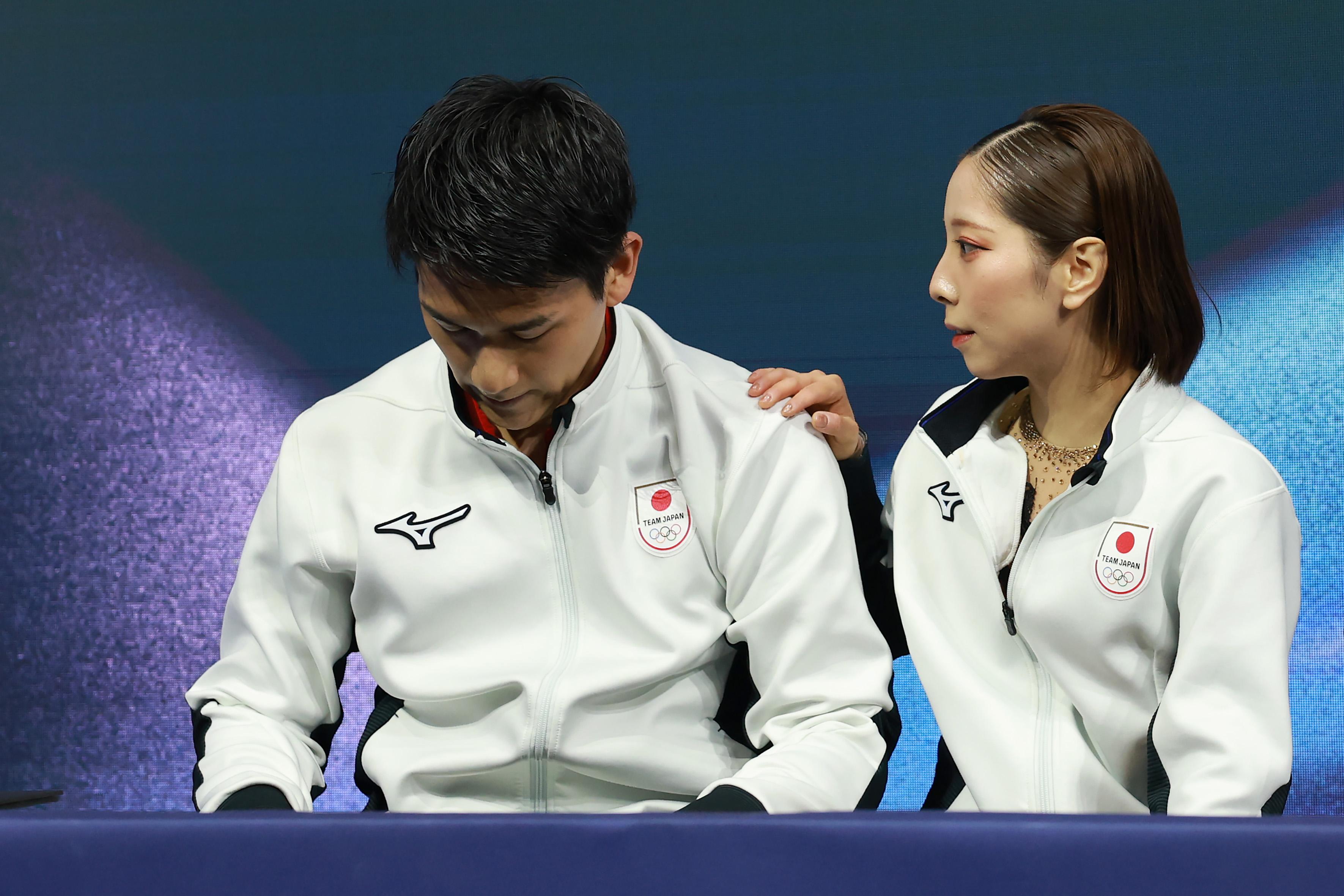 MILAN, ITALY - FEBRUARY 15: Riku Miura and partner Ryuichi Kihara of Team Japan look dejected in the Kiss and Cry zone after competing in Pair Skating - Short Program on day nine of the Milano Cortina 2026 Winter Olympic games at Milano Ice Skating Arena on February 15, 2026 in Milan, Italy. (Photo by Elsa/Getty Images)