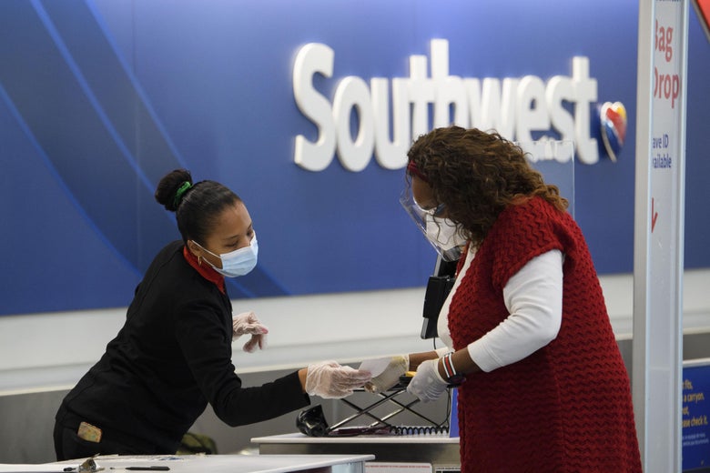 Two women wearing masks confer in front of a Southwest logo.