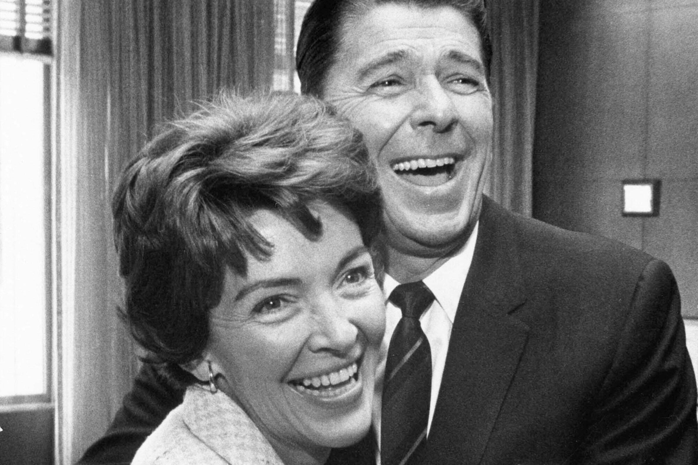 Nancy and Ronald Reagan laughing as Ronald puts his arms around Nancy